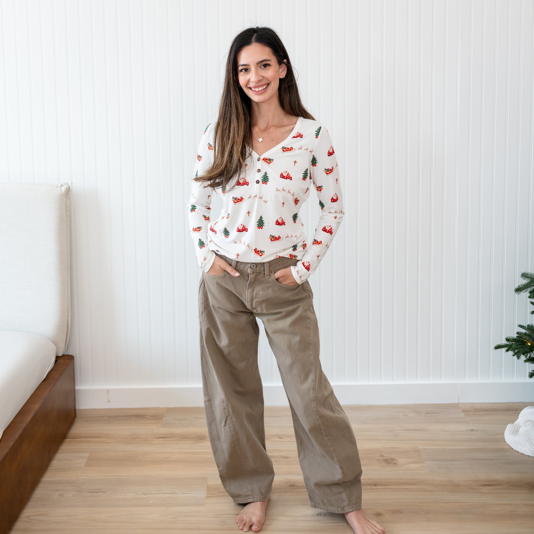 Female model standing with both hands in her pants pocket wearing the Women's Long Sleeve Henley Tee in Santa Sleigh
