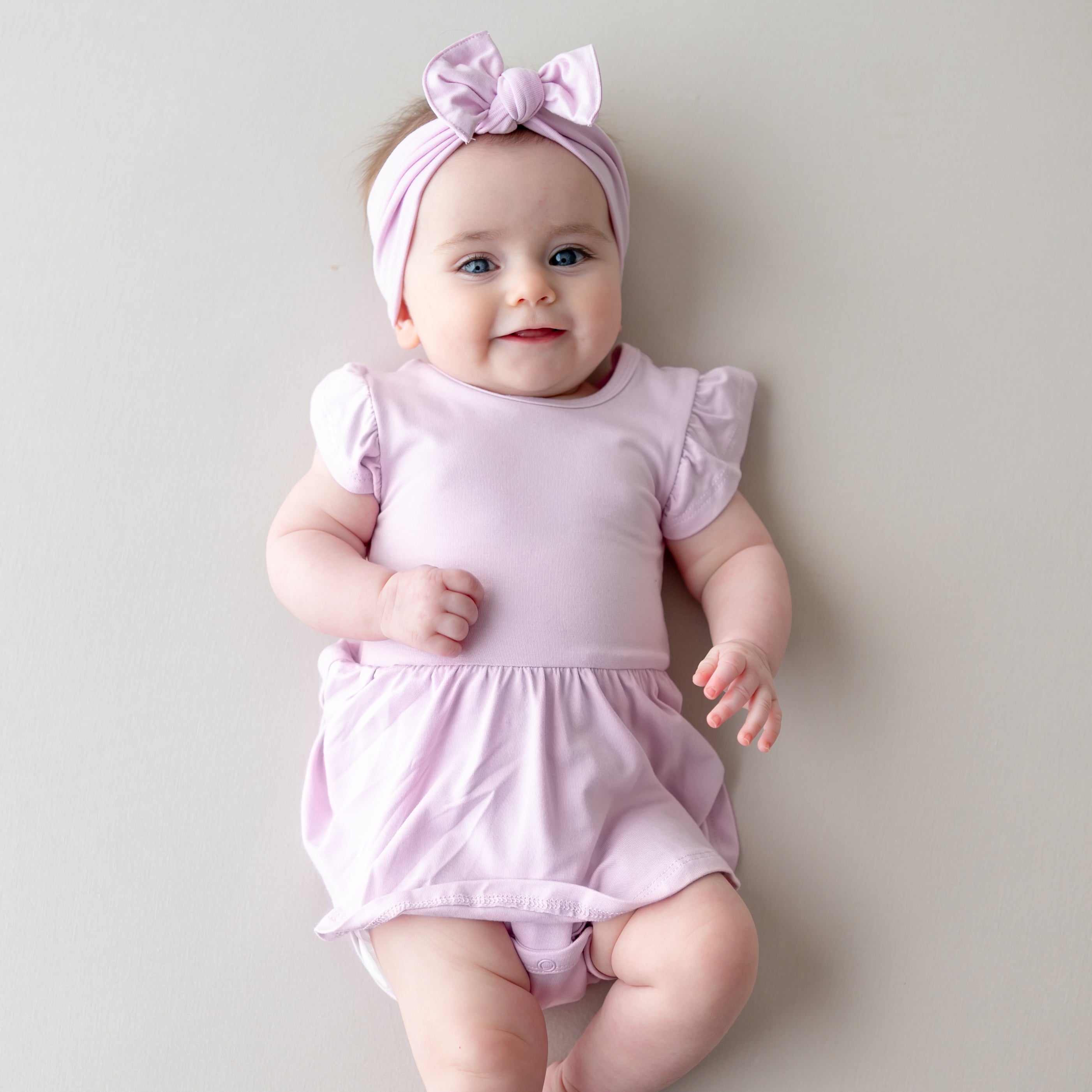 Baby wearing a light purple twirl bodysuit dress with matching bow