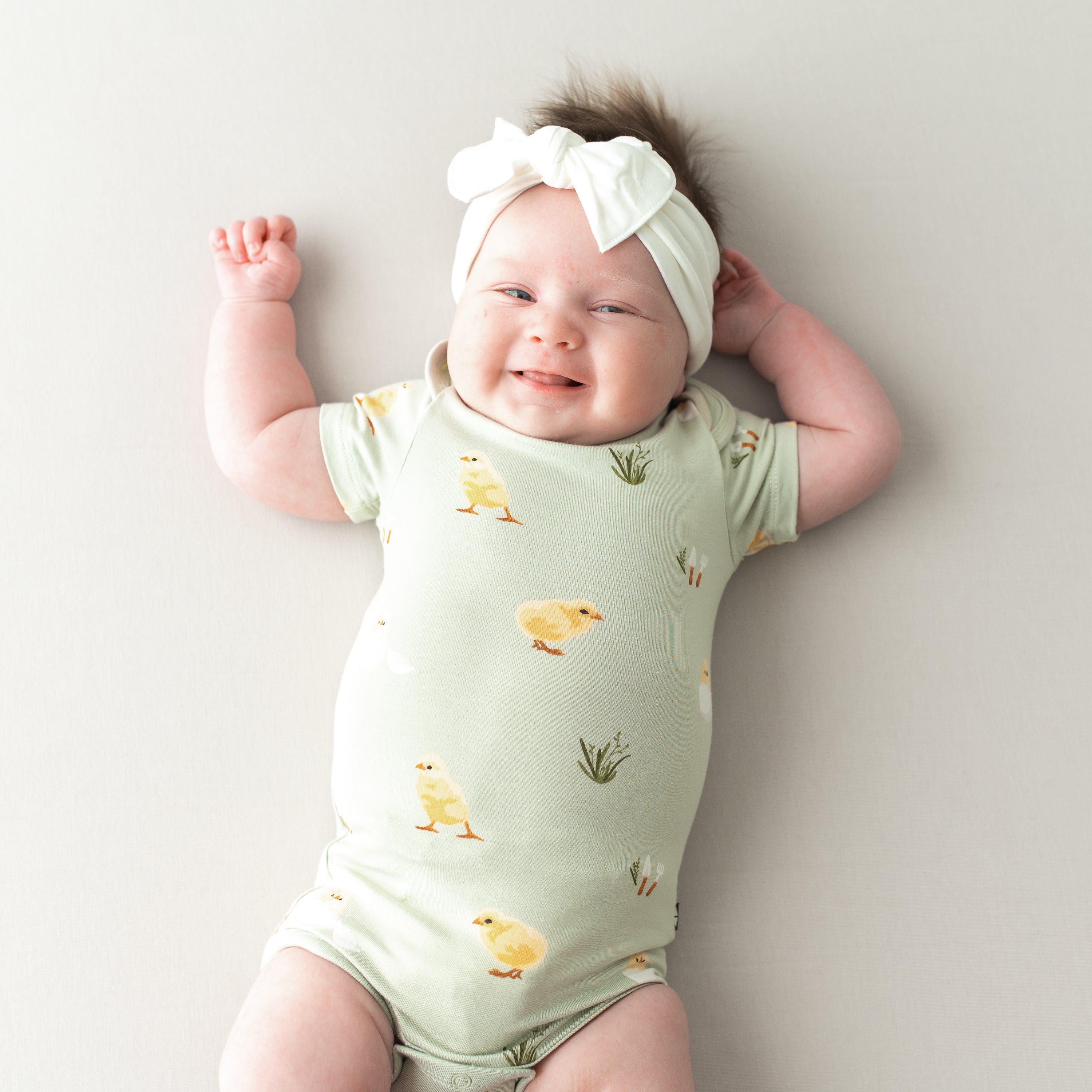 Baby in Bodysuit in Aloe Chick and cloud bow