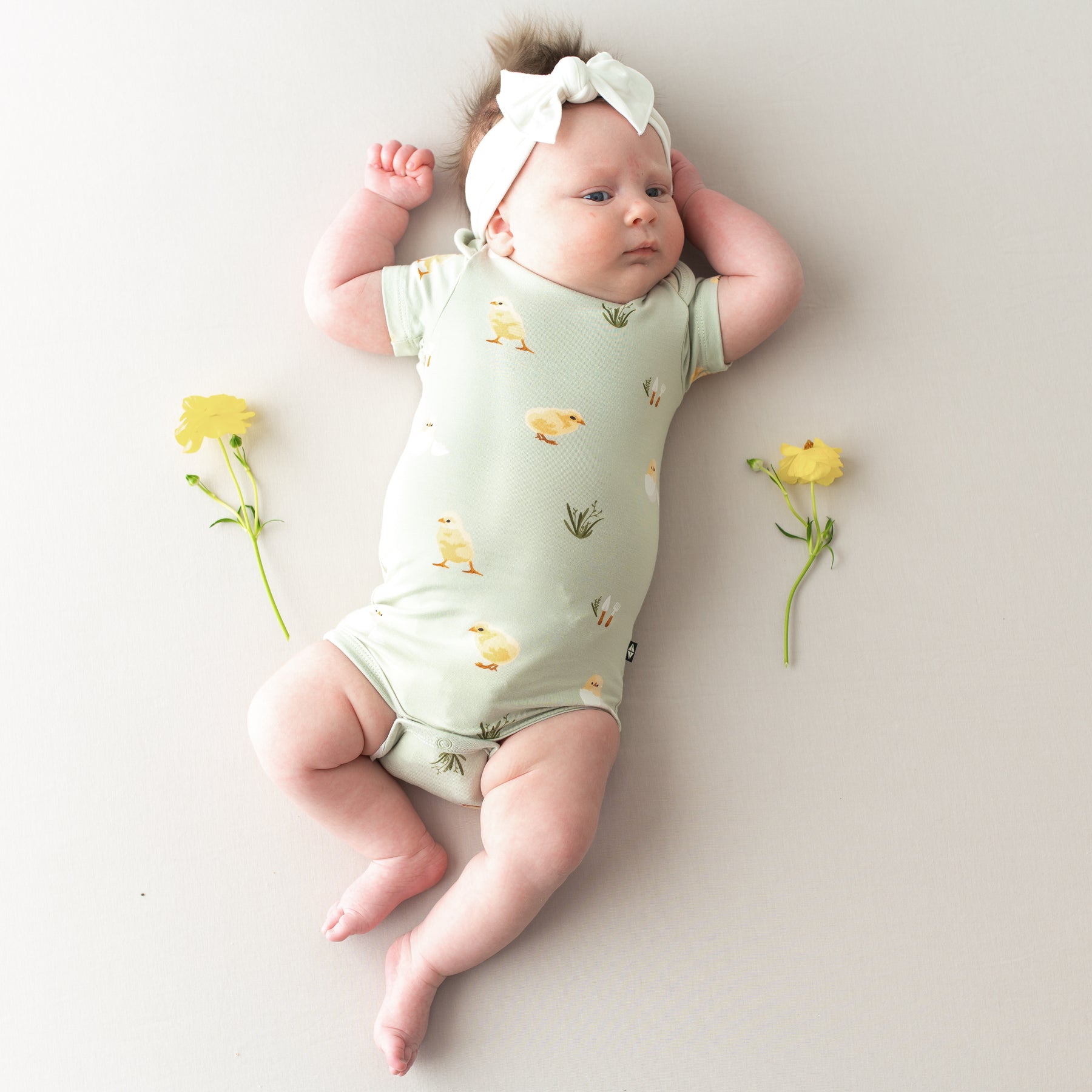 Baby in Bodysuit in Aloe Chick and cloud bow