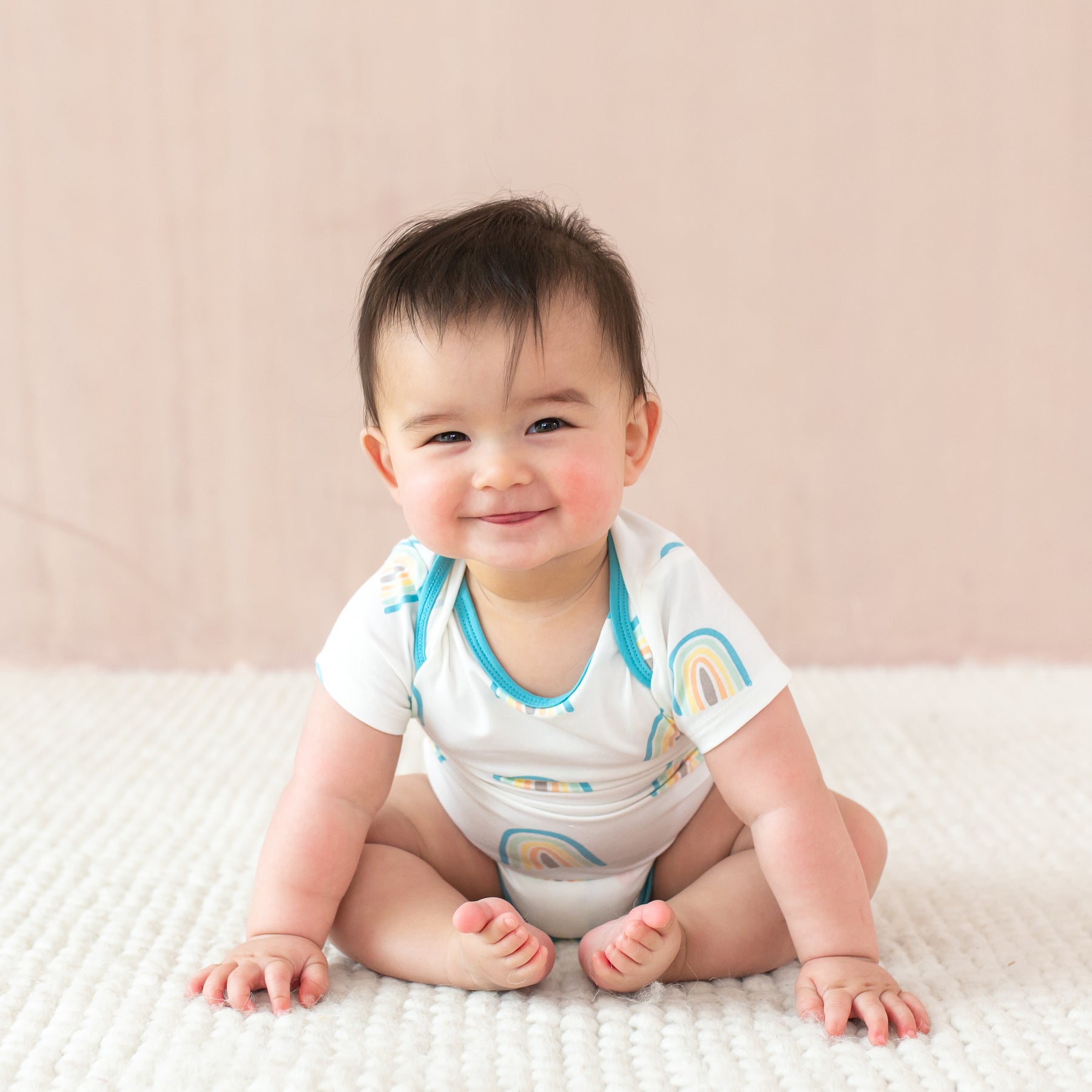 Baby smiling wearing Bodysuit in Makai Rainbow