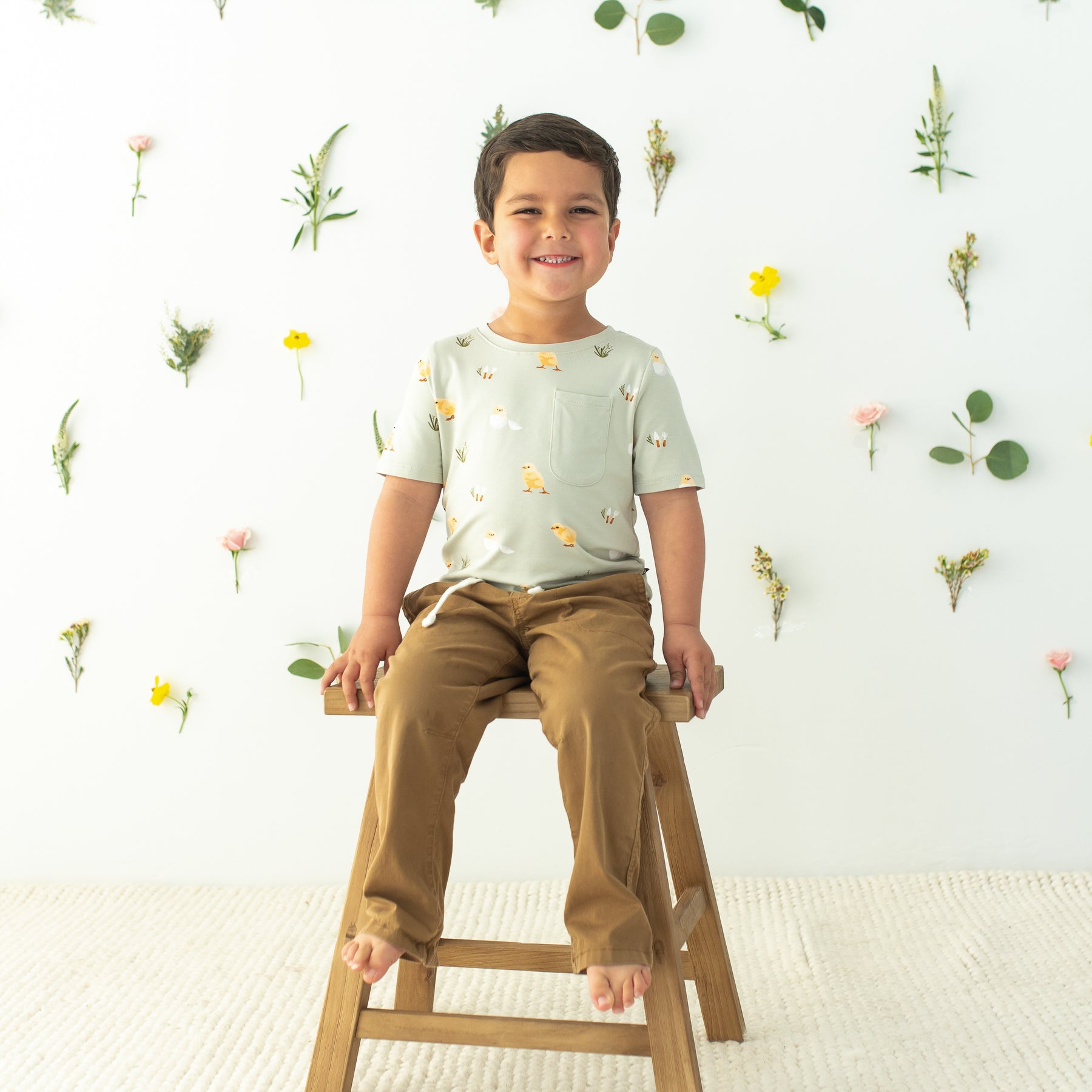 Toddler sitting on stool wearing Toddler Crew Neck Tee in Aloe Chick