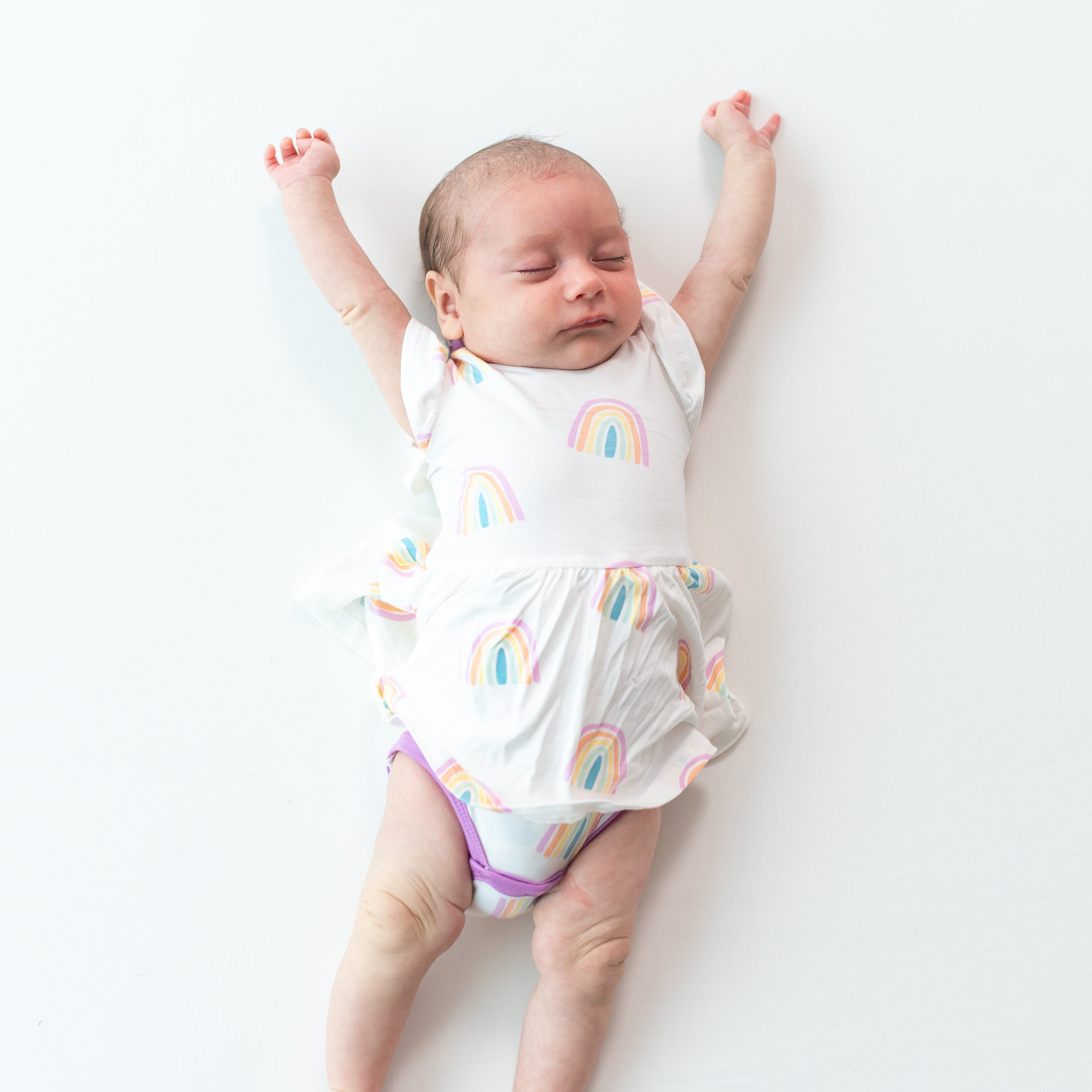 Baby stretching and wearing Twirl Bodysuit Dress in Poi Rainbow 