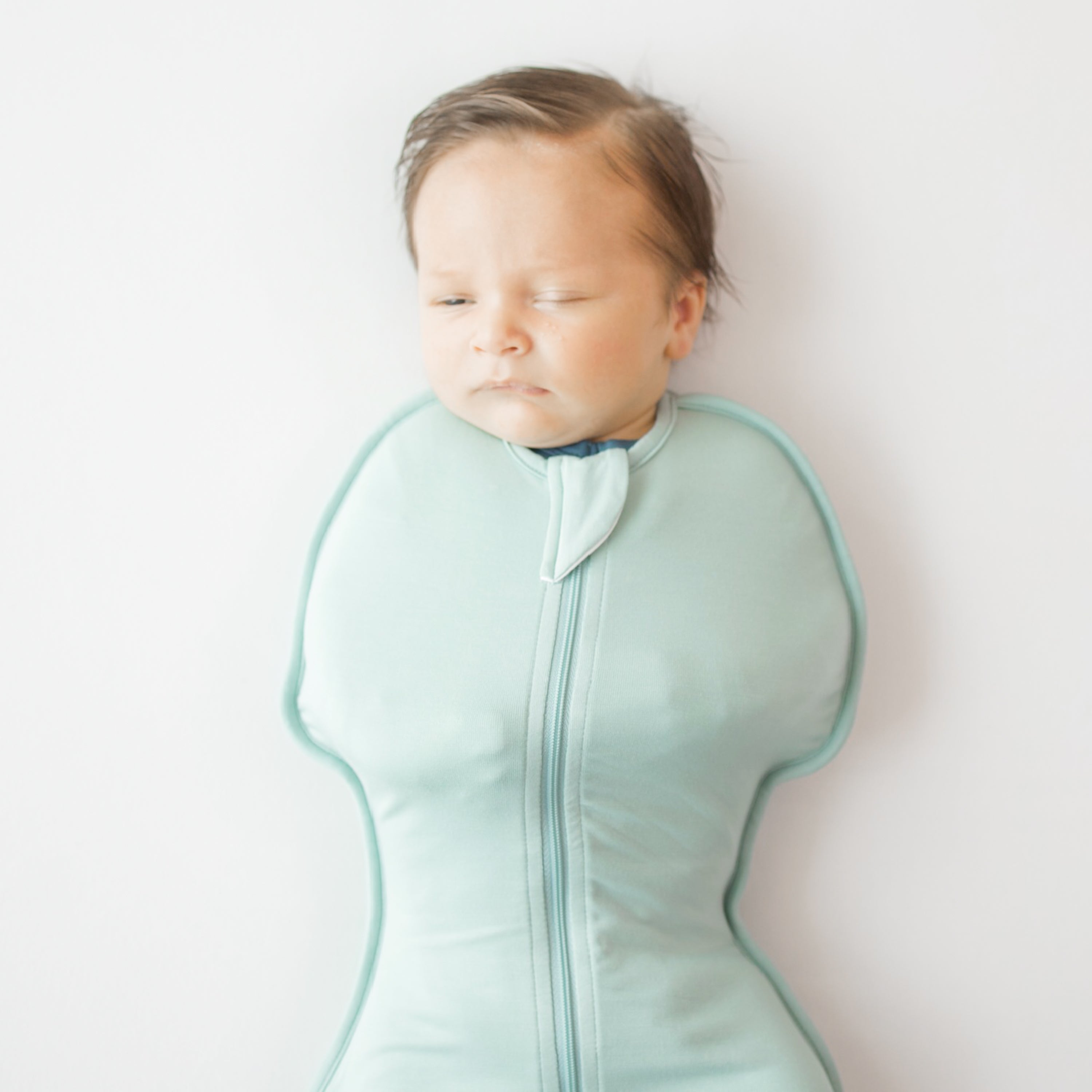 Close up of baby wearing Swaddle Bag in Sage 0.5