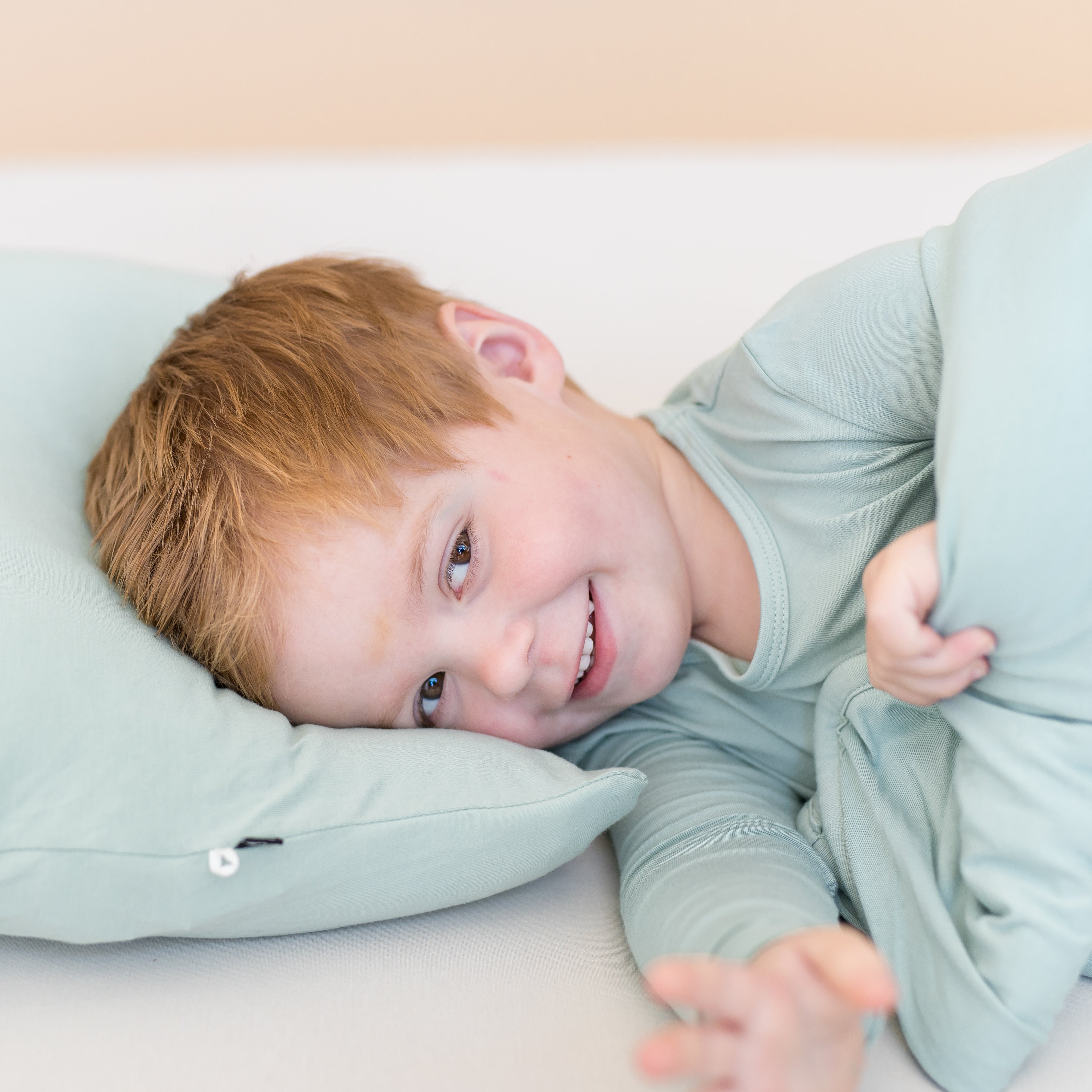 Toddler laying on a sage green pillow