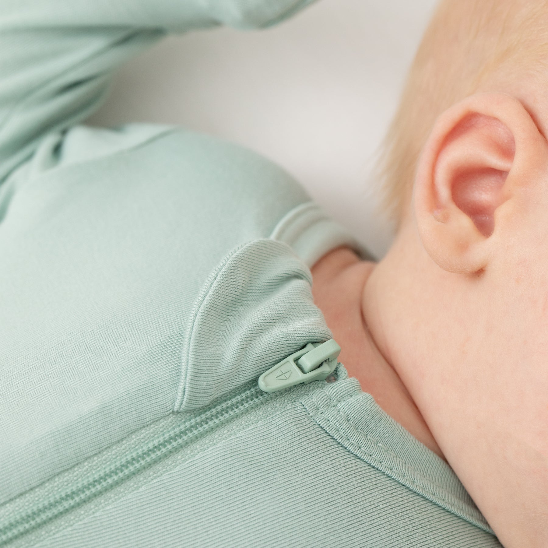 Close up of the zipper garage and logo zipper on the Zippered Footie in Sage