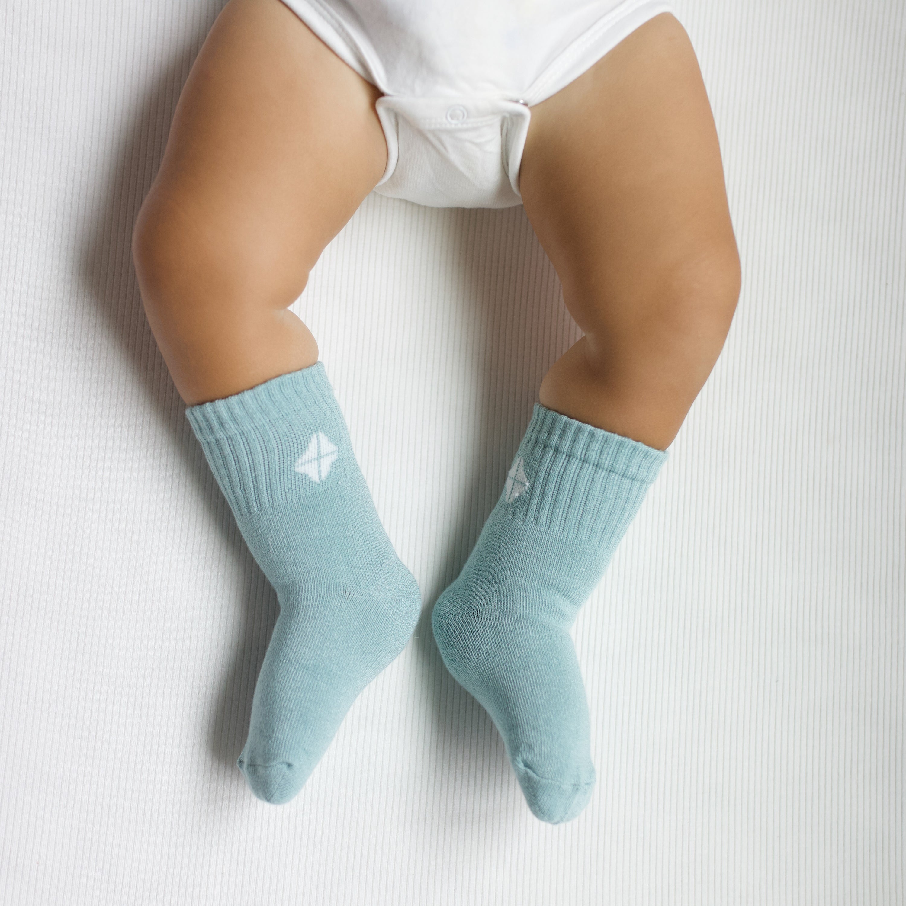 Crew Socks in Sage shown on an infant model with the Kyte Baby logo visible