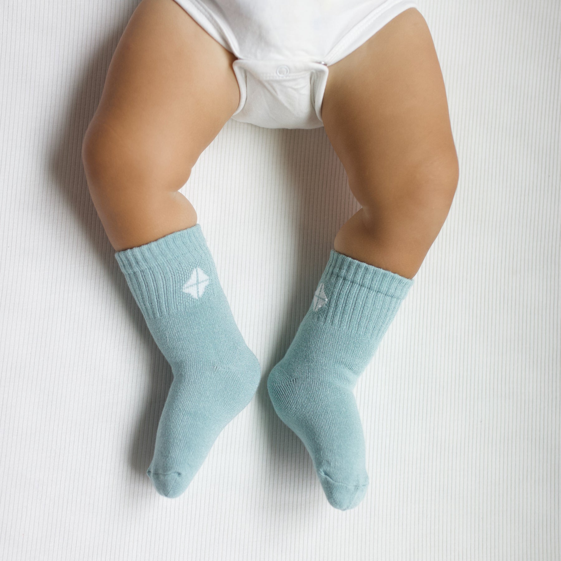 Crew Socks in Sage shown on an infant model with the Kyte Baby logo visible