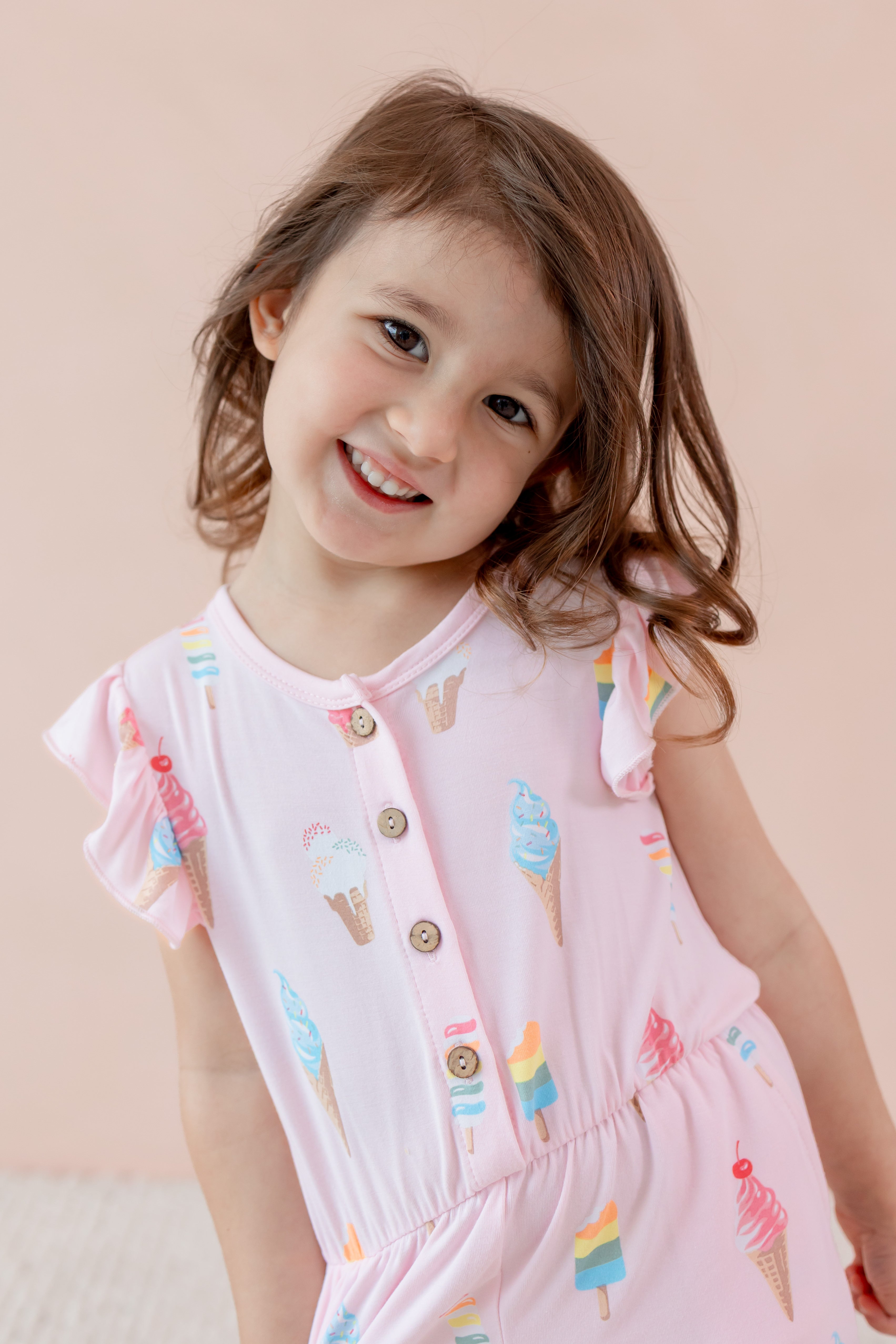 Child posing in Sakura Ice cream print Flutter Sleeve Romper on a beige background