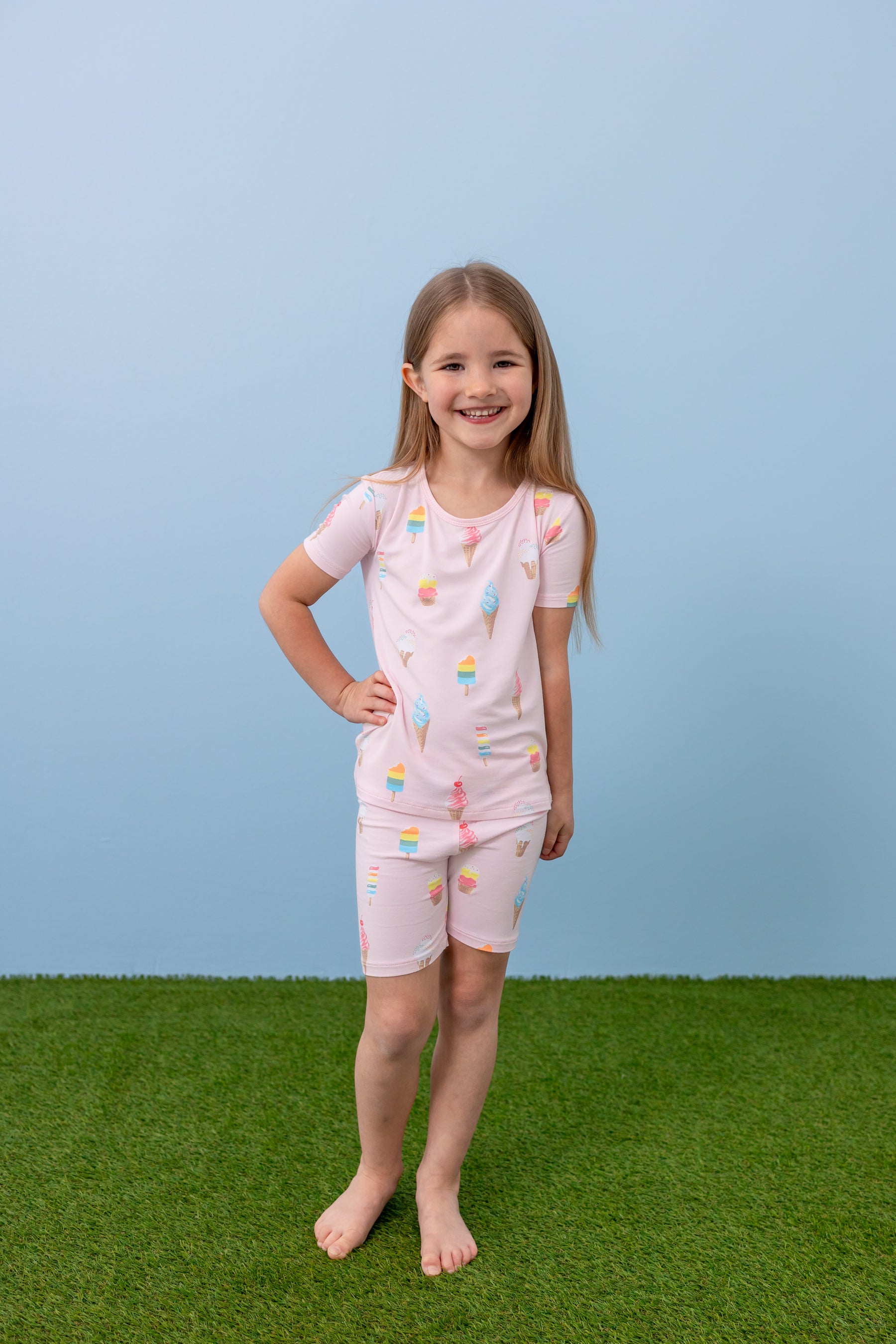 Child standing in Sakura Ice Cream print short sleeve pajama set on blue background and green grass