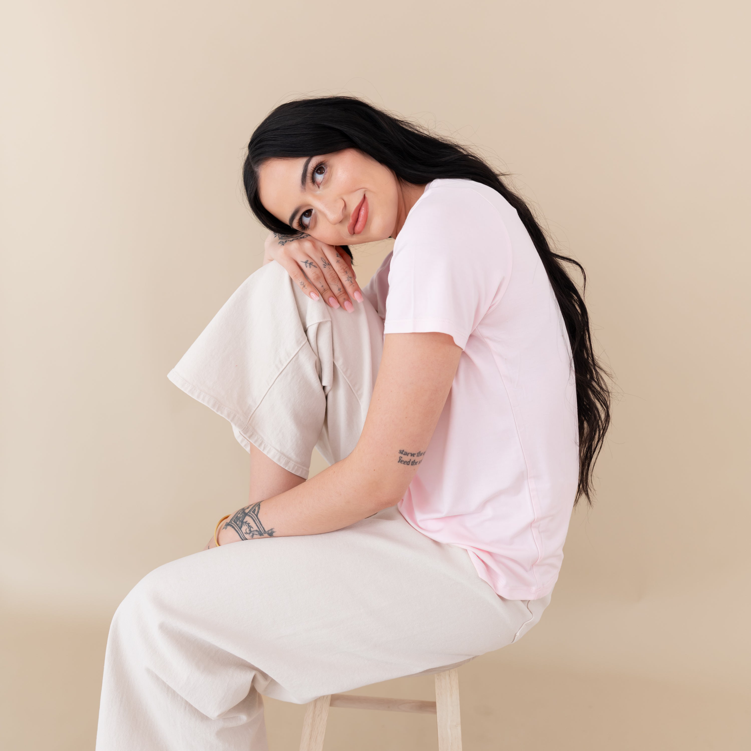 Woman modeling Women's Crew Neck Tee in Sakura with head on knee