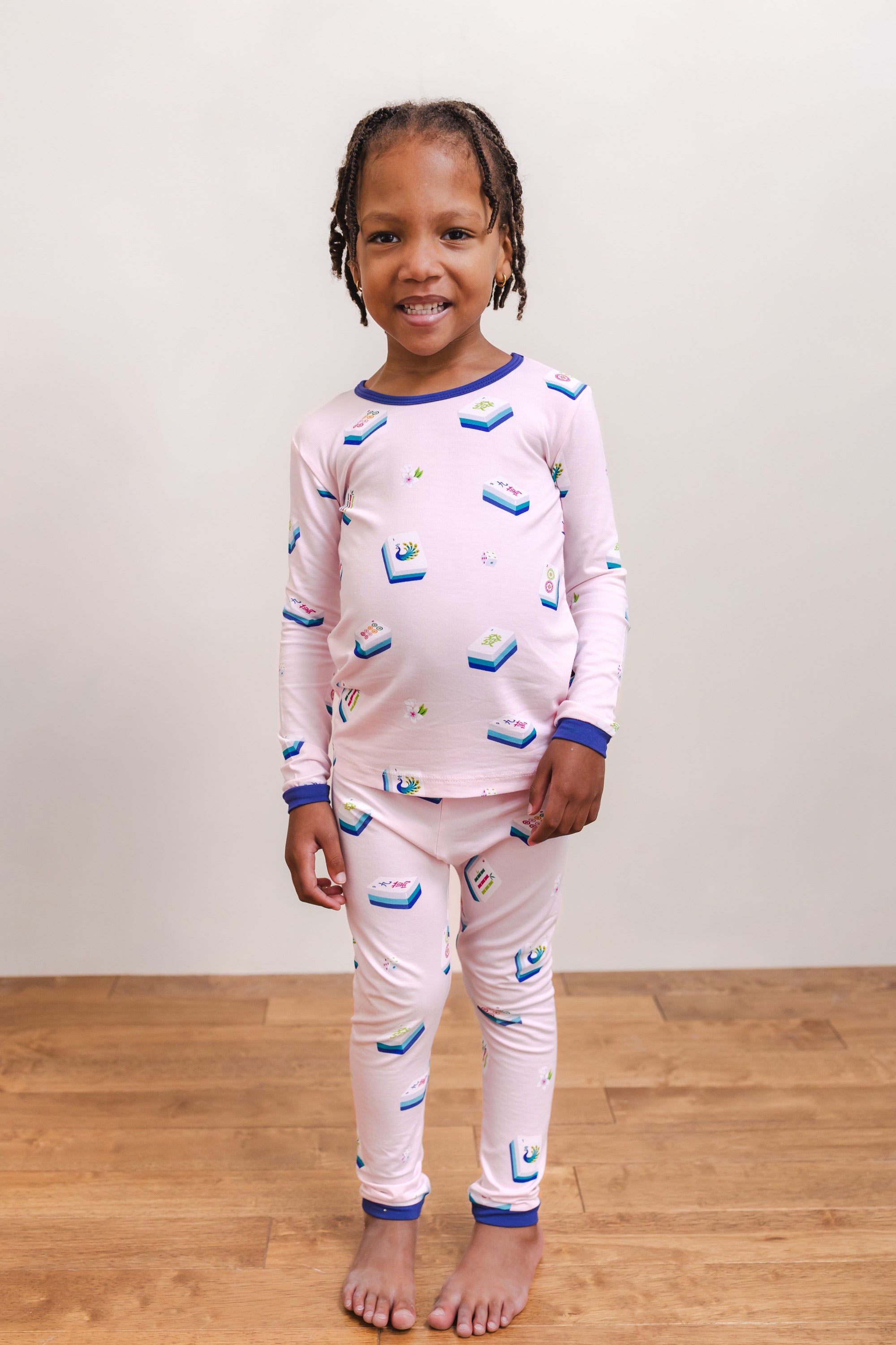 Girl wearing Long Sleeve Pajamas in Sakura Mahjong print standing against a beige background