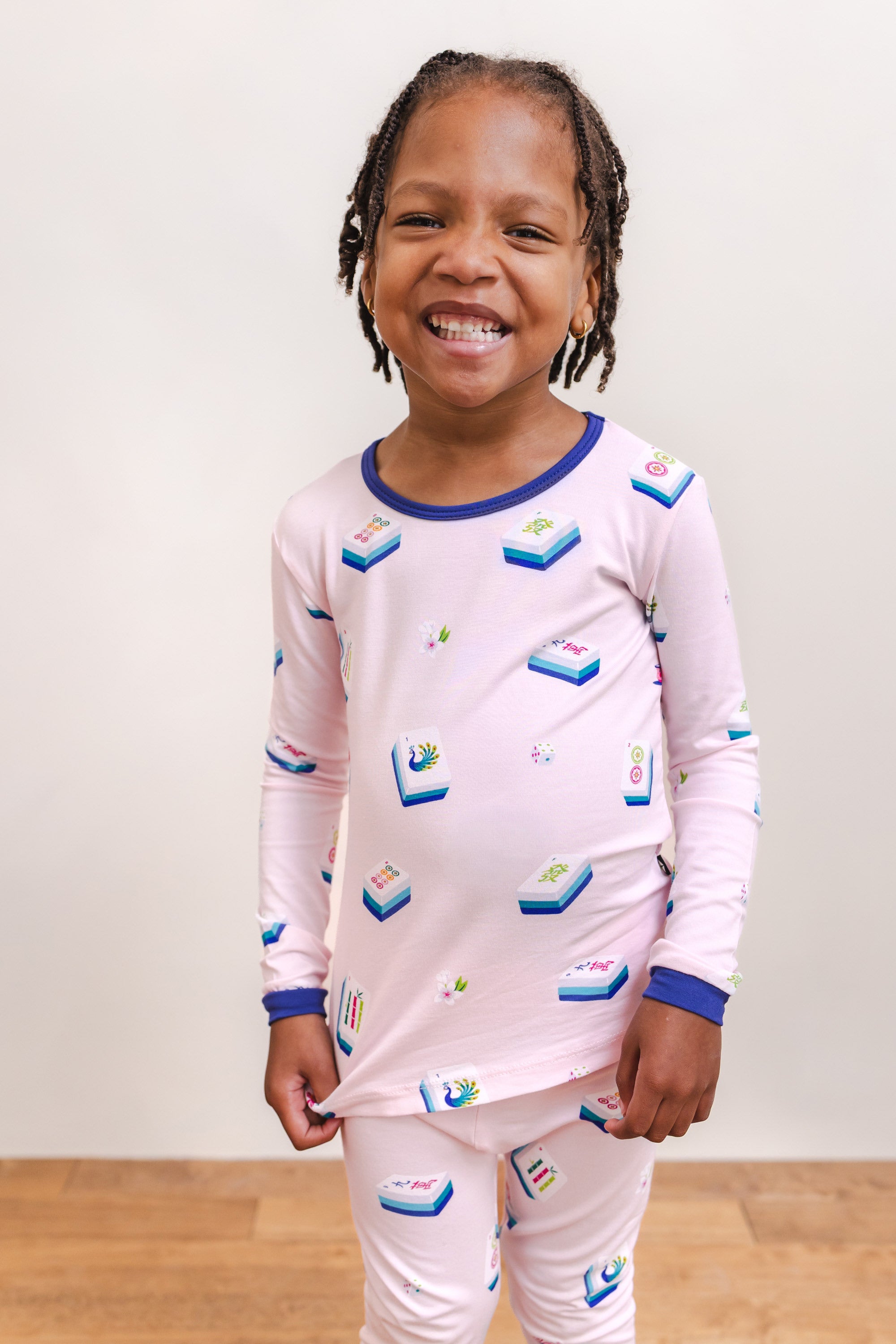 Girl smiling in Long Sleeve Pajamas in Sakura Mahjong print standing against a beige background