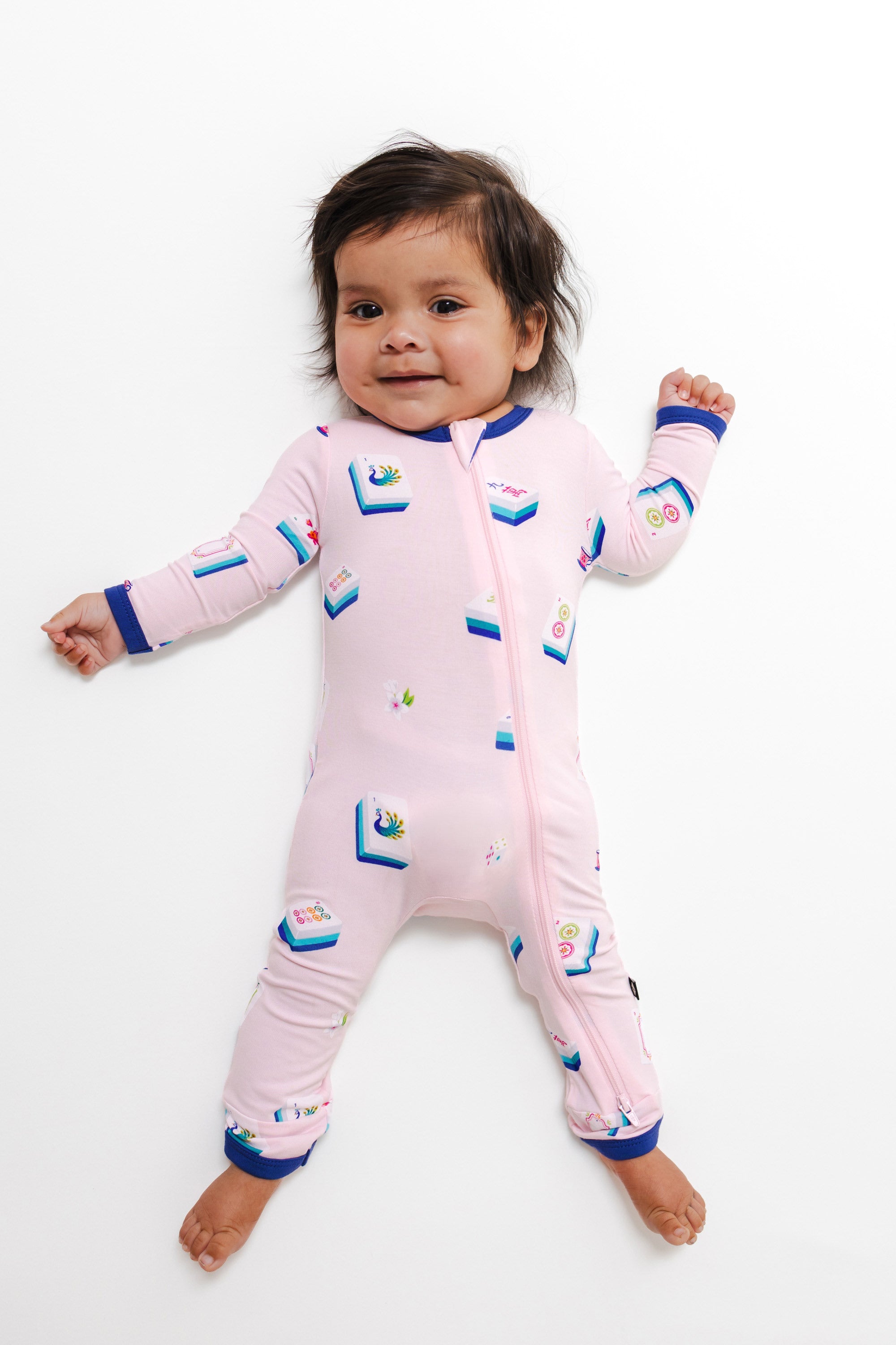 Baby wearing Zippered Romper in Sakura Mahjong print on a white background