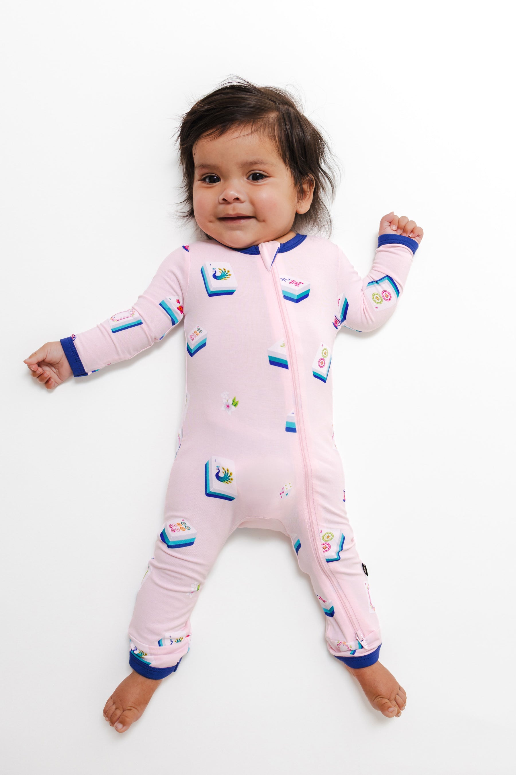 Baby wearing Zippered Romper in Sakura Mahjong print on a white background