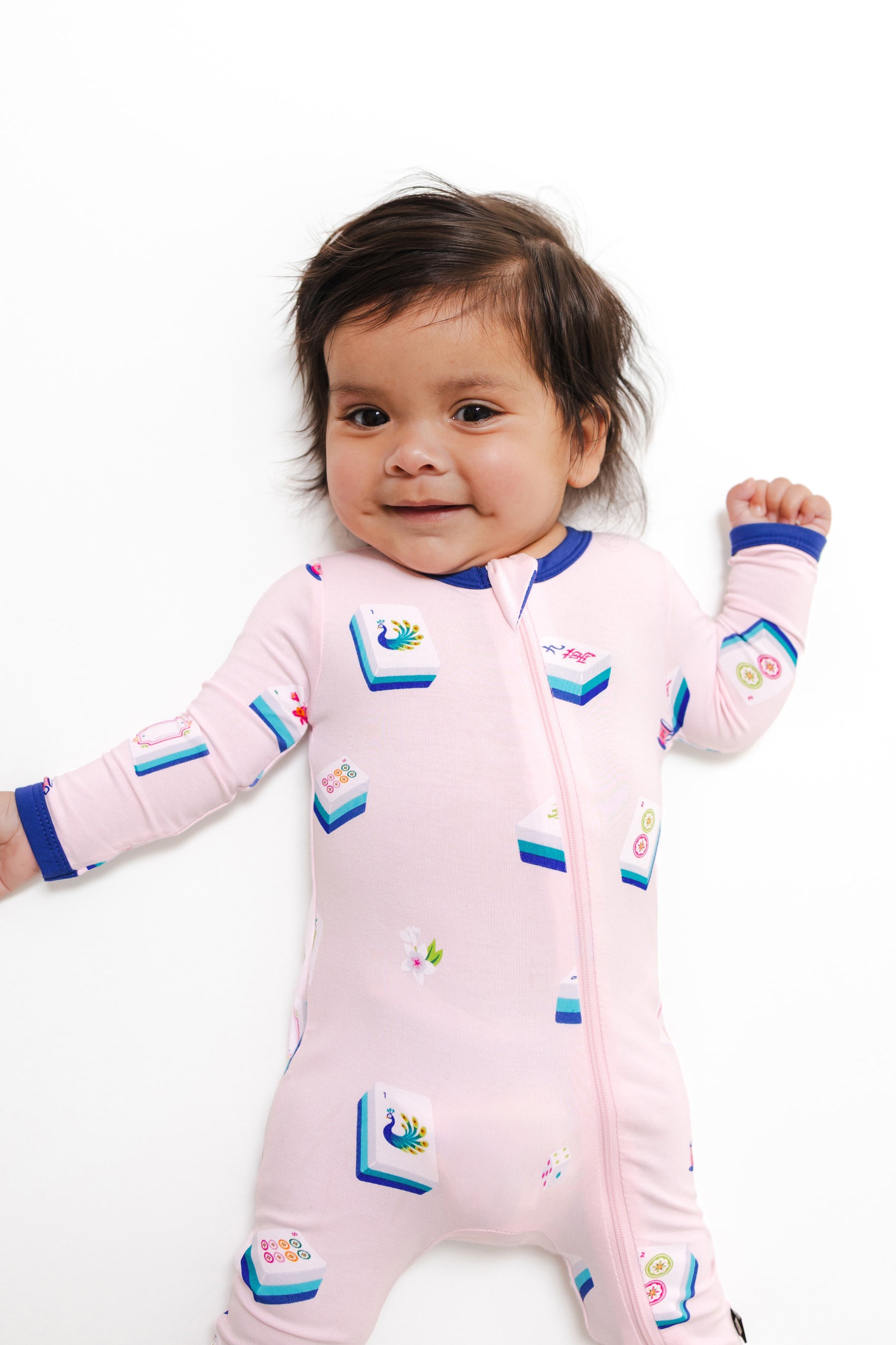close up of Baby wearing Zippered Romper in Sakura Mahjong print on a white background