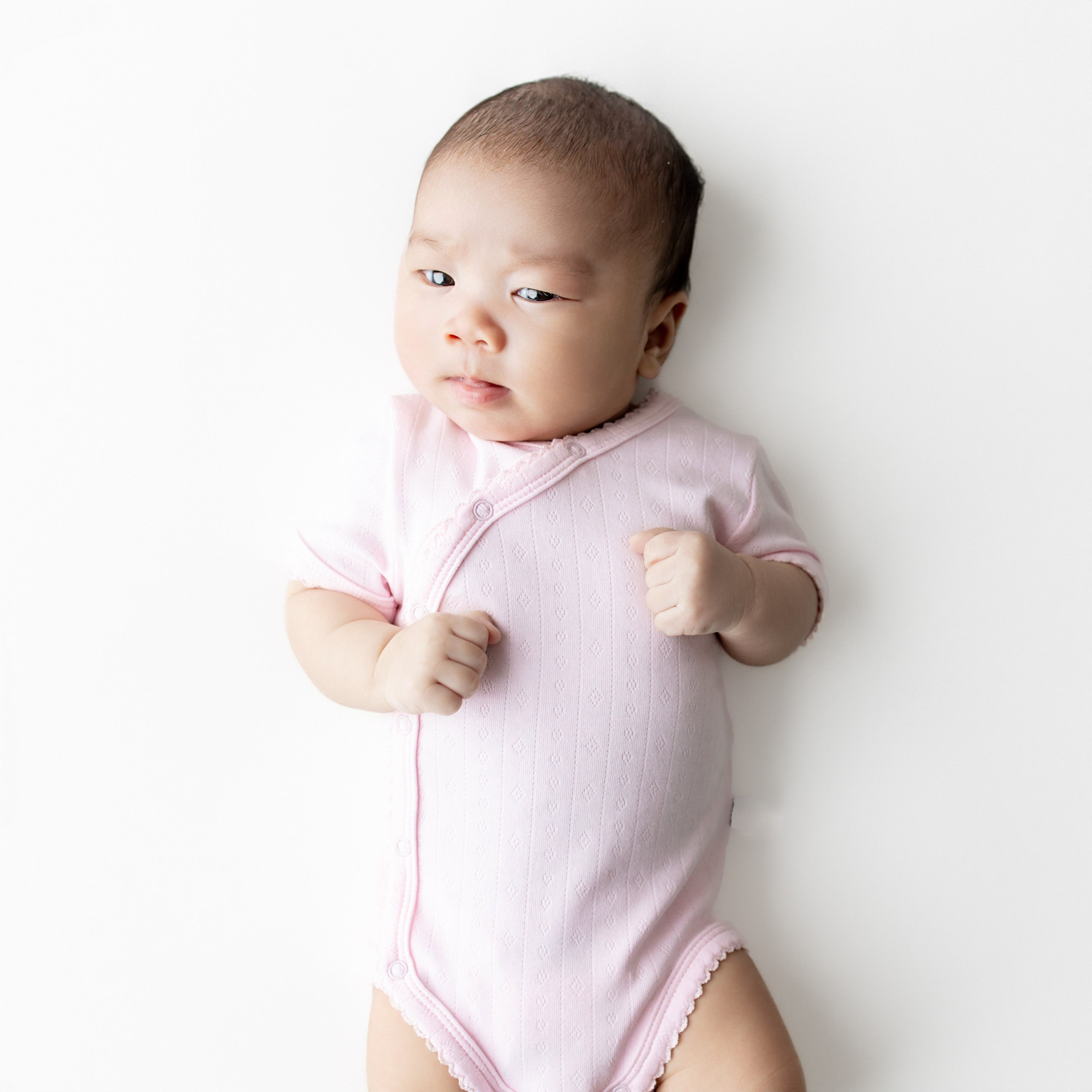Close up of a newborn wearing the Pointelle Kimono Bodysuit in Sakura showing the picot trim