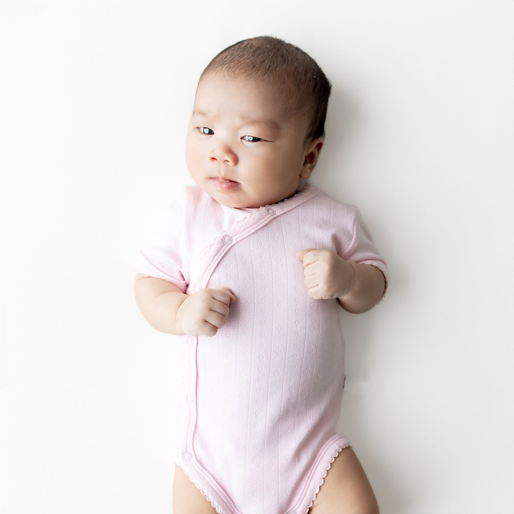 Close up of a newborn wearing the Pointelle Kimono Bodysuit in Sakura showing the picot trim