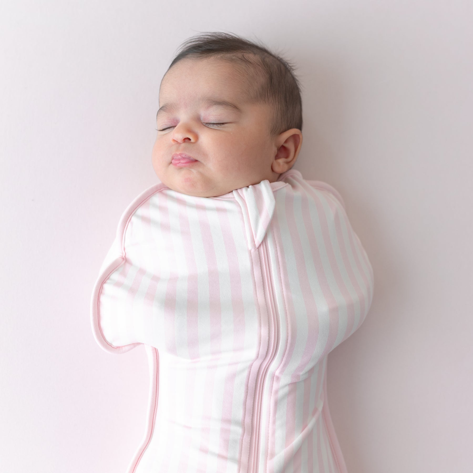 Close up of sleeping newborn wearing the Swaddle Bag in Small Sakura Stripe 0.5