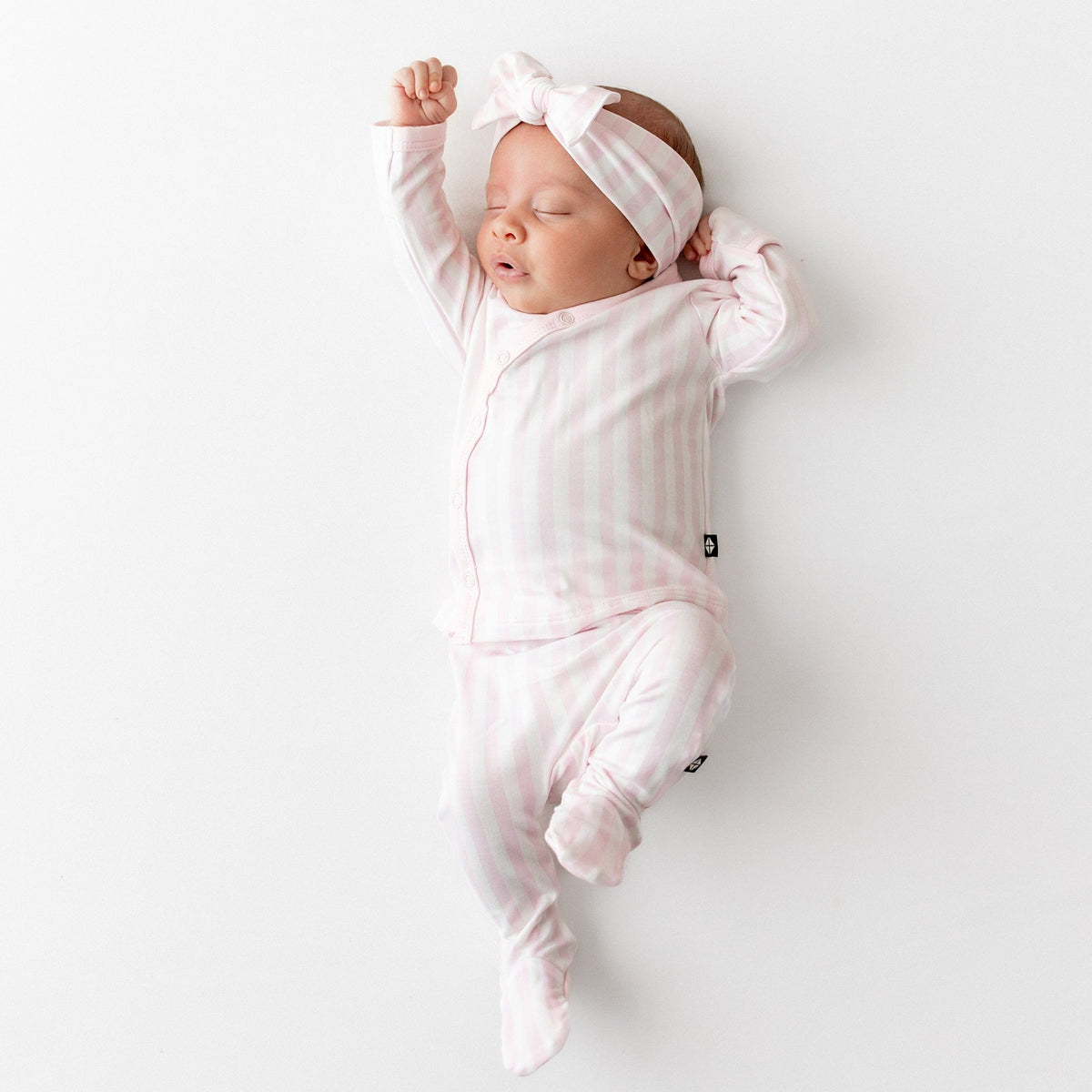 Sleeping newborn wearing the soft and breathable Take Me Home Set with Bow in Small Sakura Stripe