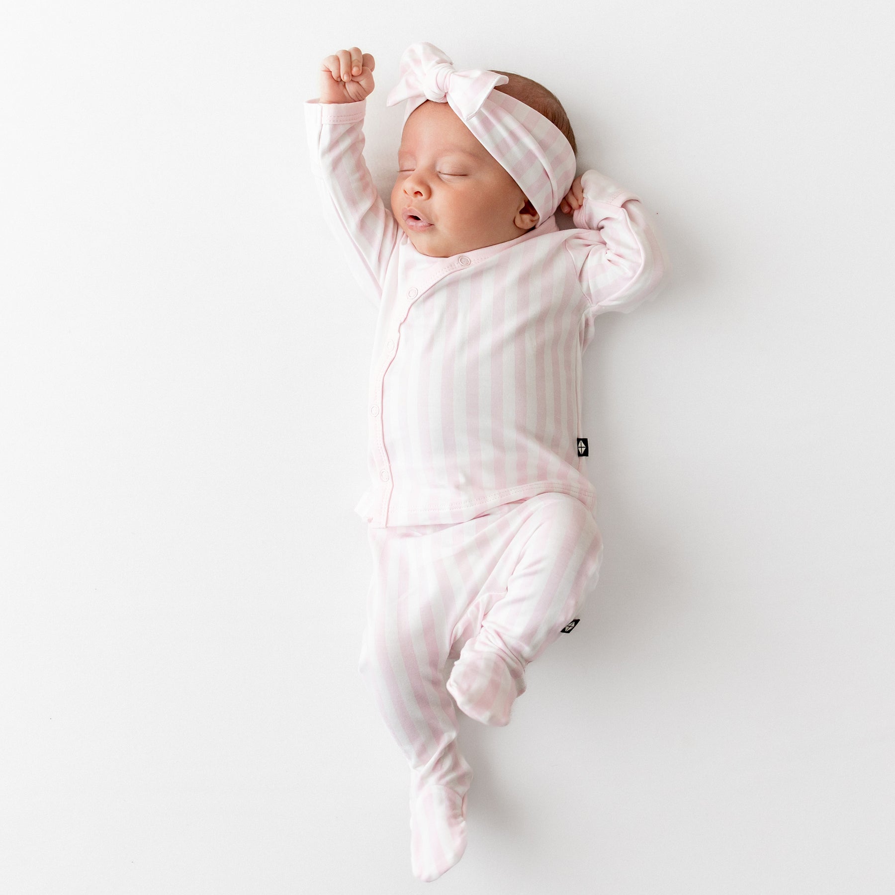Sleeping newborn wearing the soft and breathable Take Me Home Set with Bow in Small Sakura Stripe