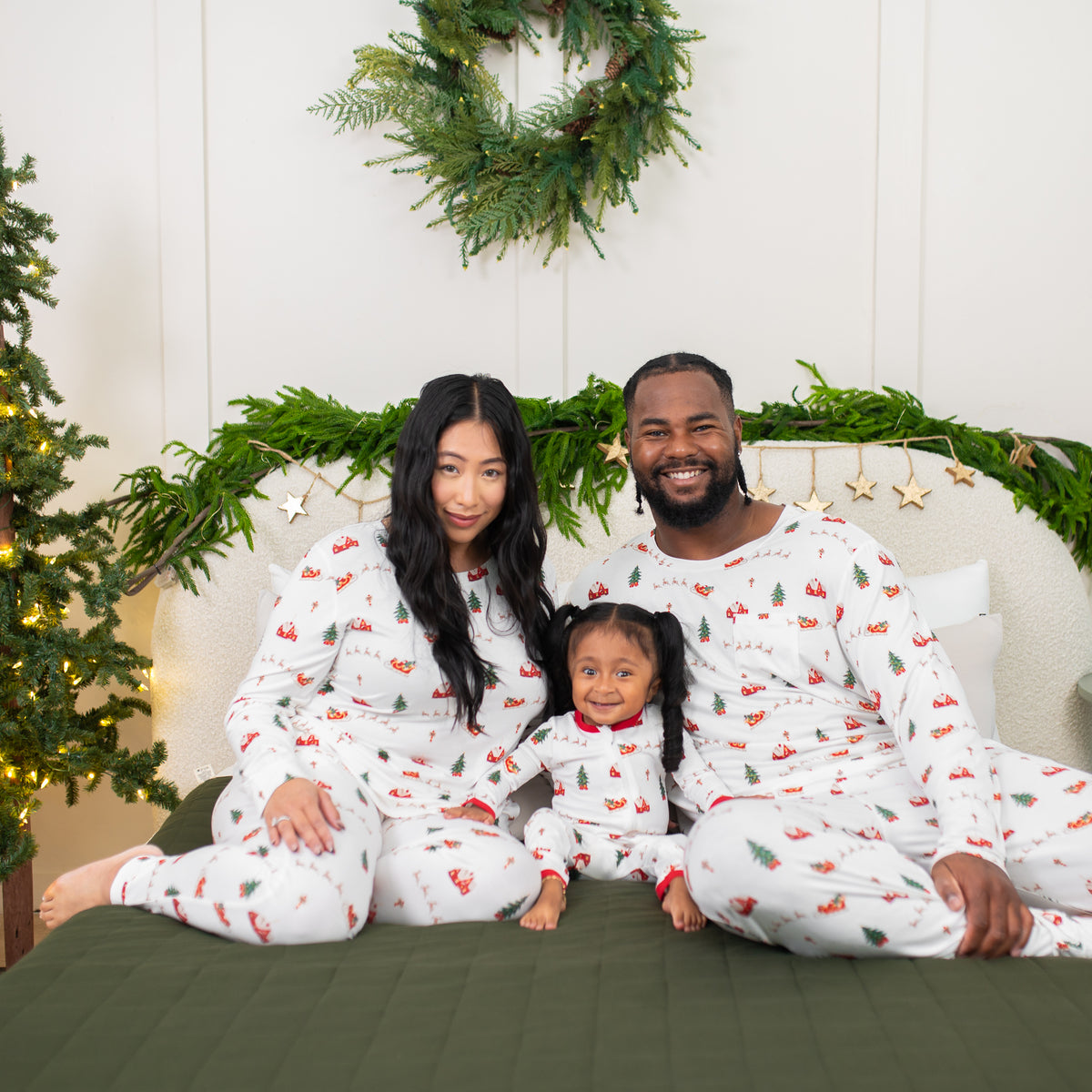 Family of three sitting on a bed matching in Santa Sleigh
