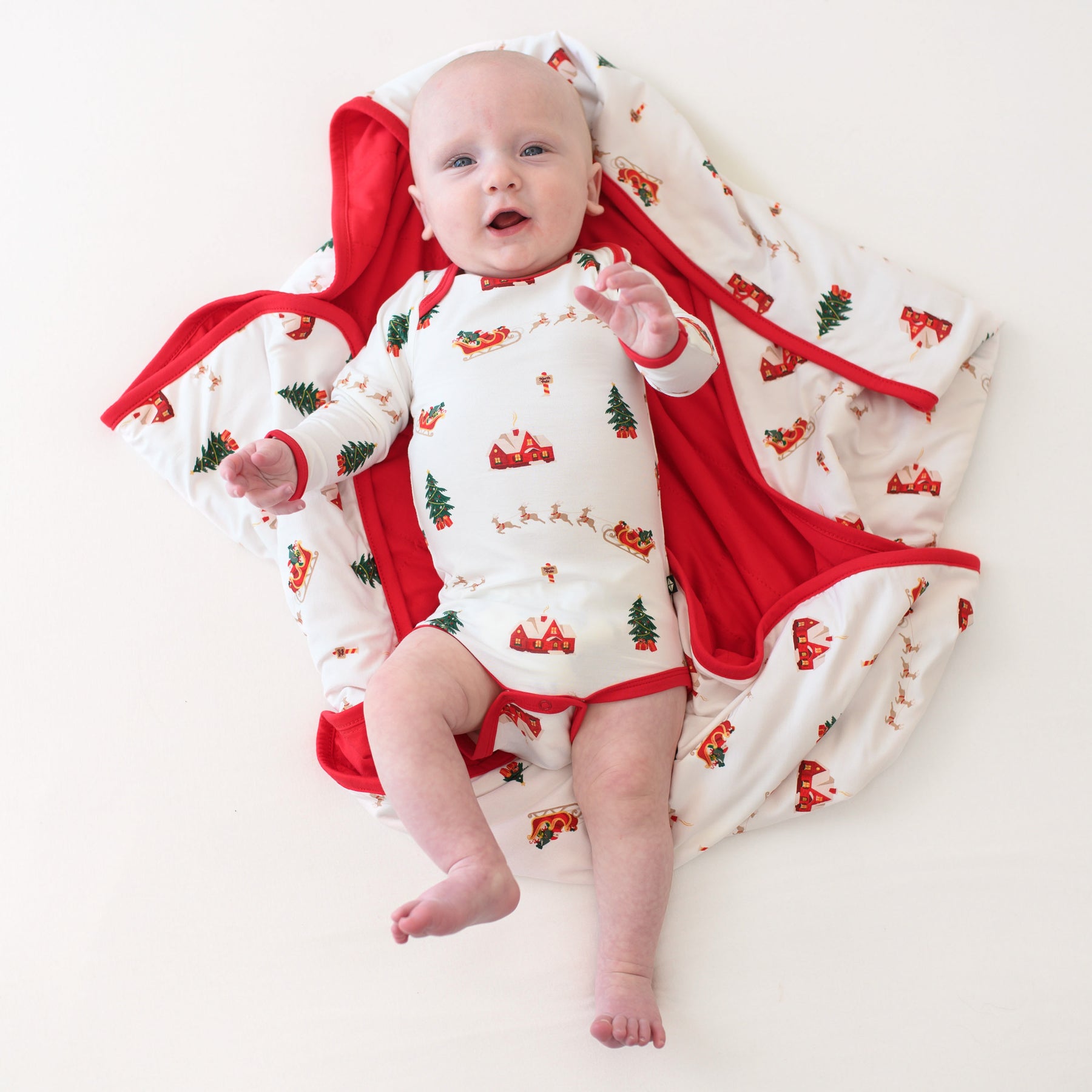 Infant laying on a Baby Blanket in Santa Sleigh wearing a matching long sleeve bodysuit