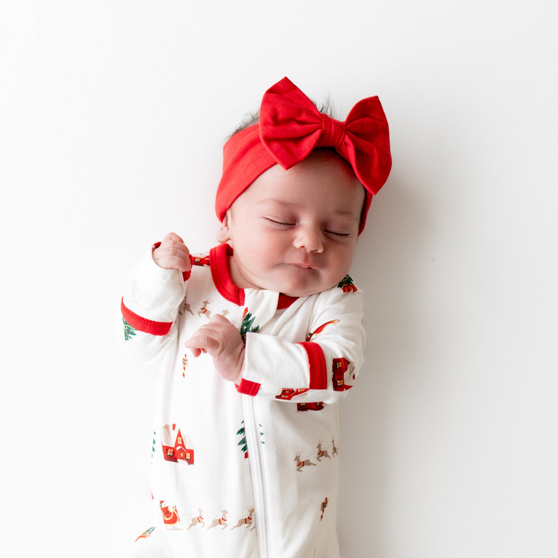 Sleeping infant wearing the Bow Headband in Cardinal and Santa Sleigh Zippered romper