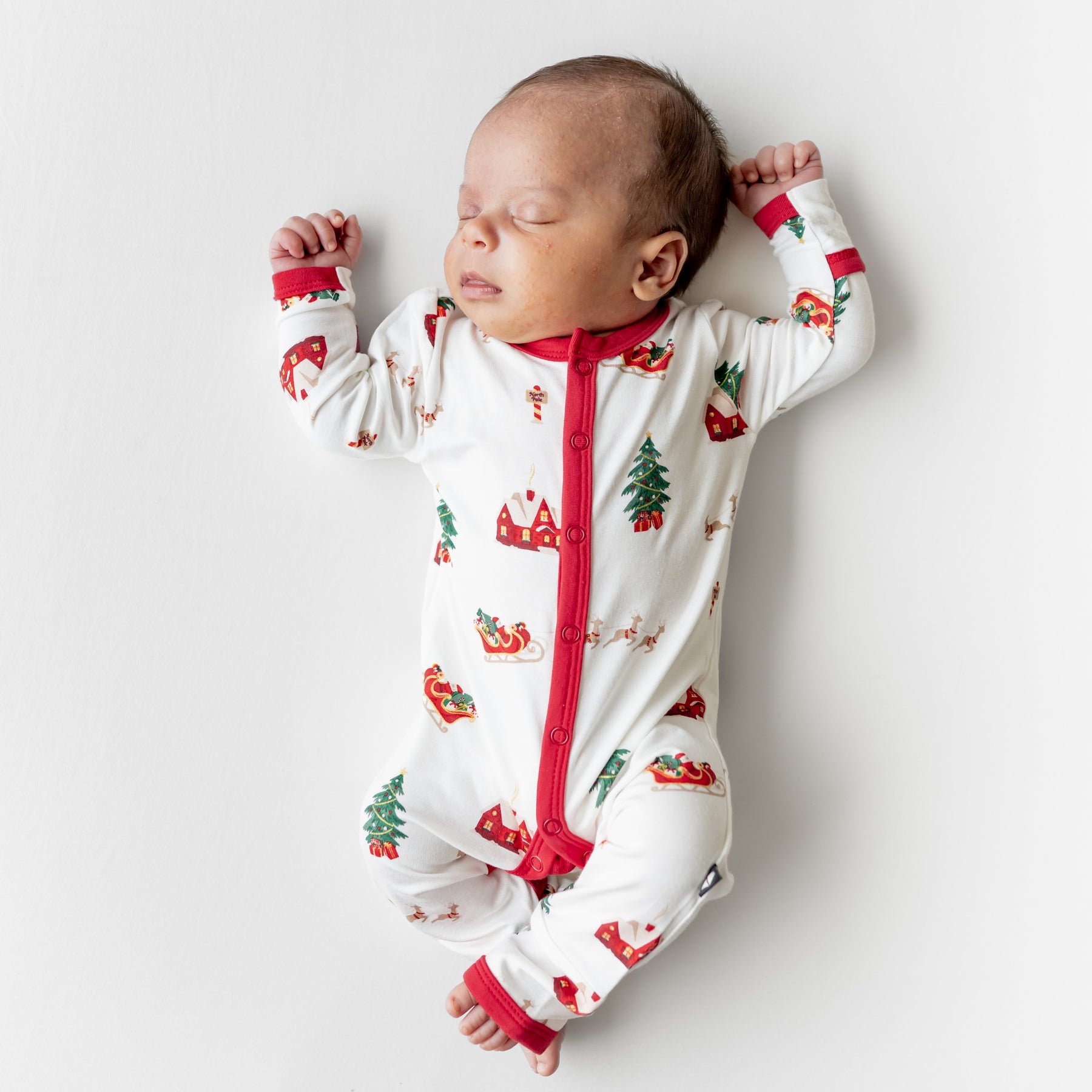 Sleeping newborn wearing the Romper in Santa Sleigh