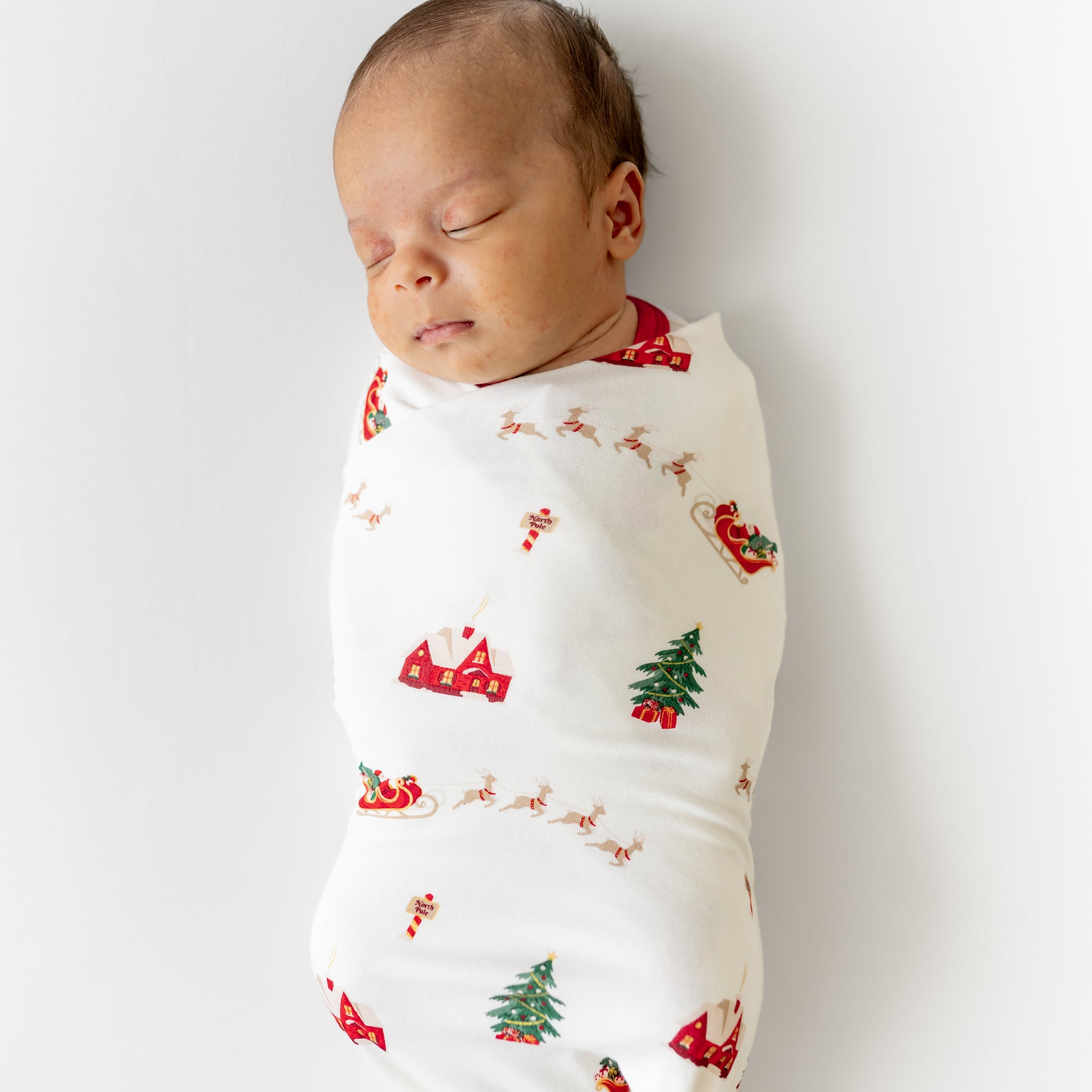 Close up of sleeping newborn swaddled in the Swaddle Blanket in Santa Sleigh