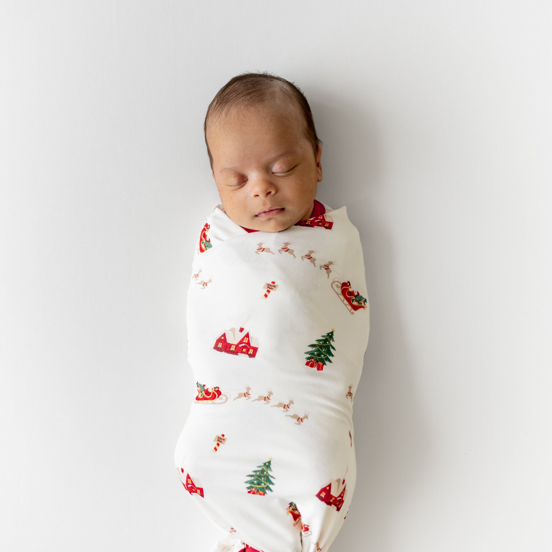 Sleeping newborn swaddled in the Swaddle Blanket in Santa Sleigh