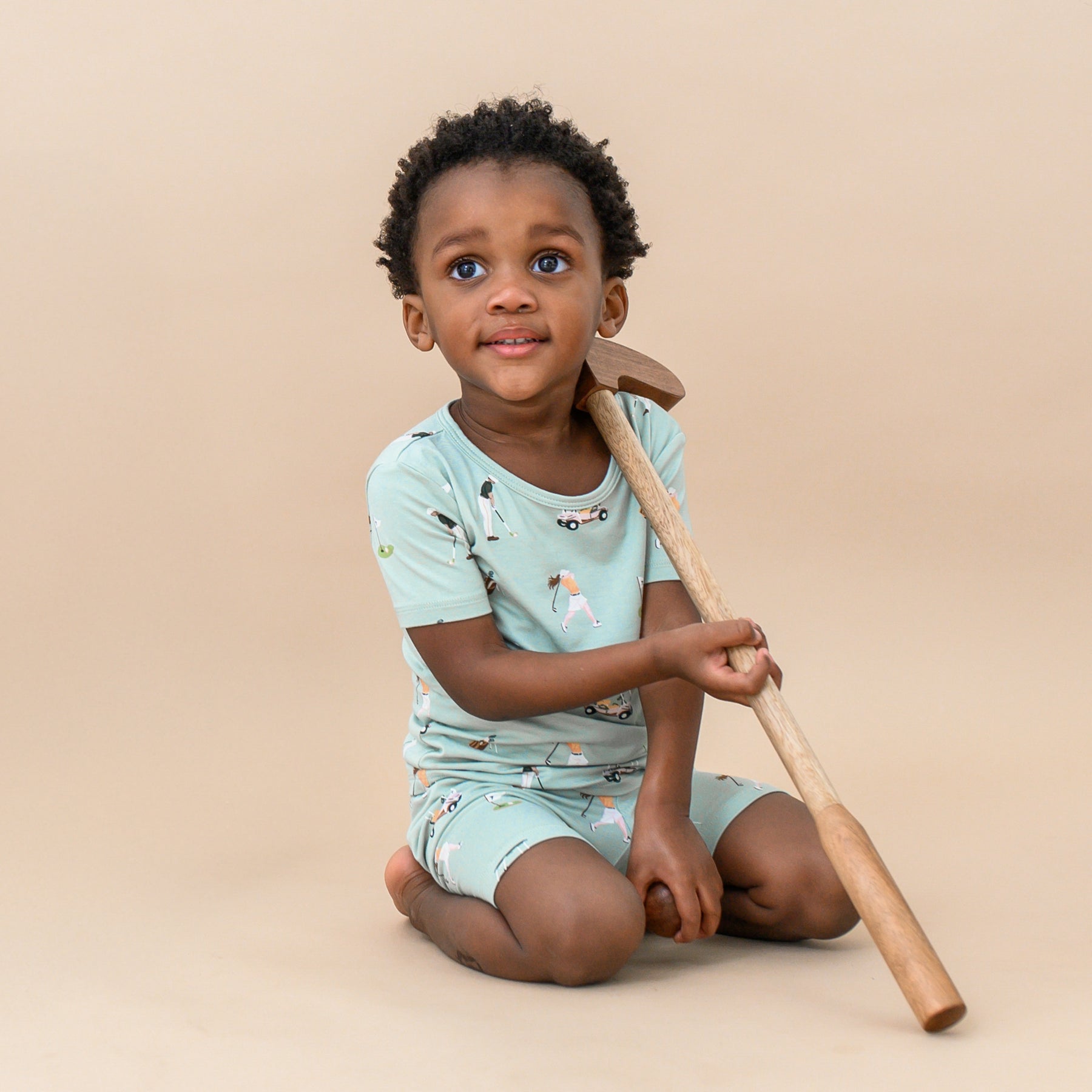 Toddler sitting wearing Short Sleeve Pajamas in Golf with toy golf club