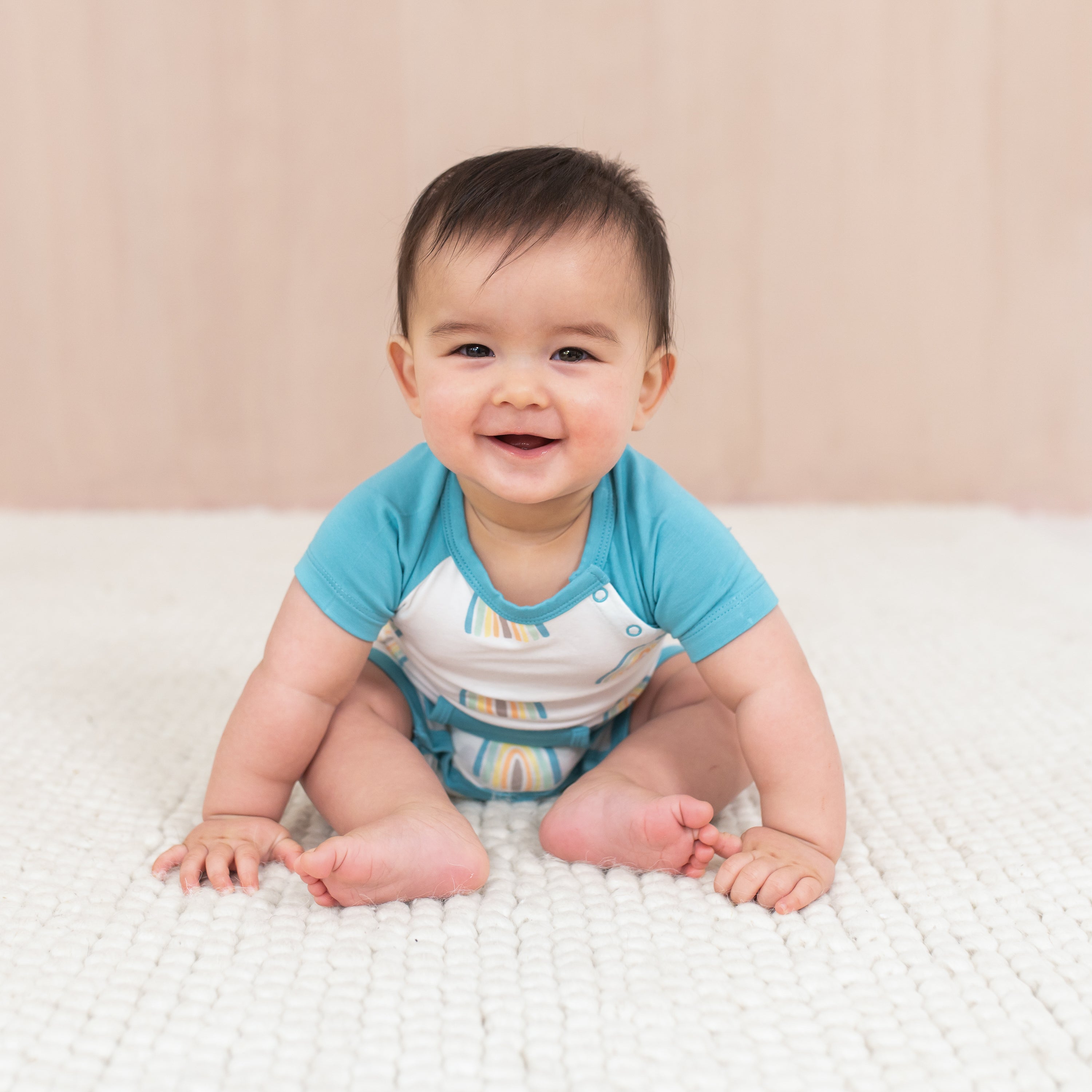 Baby leaning forward wearing Shortall in Makai Rainbow