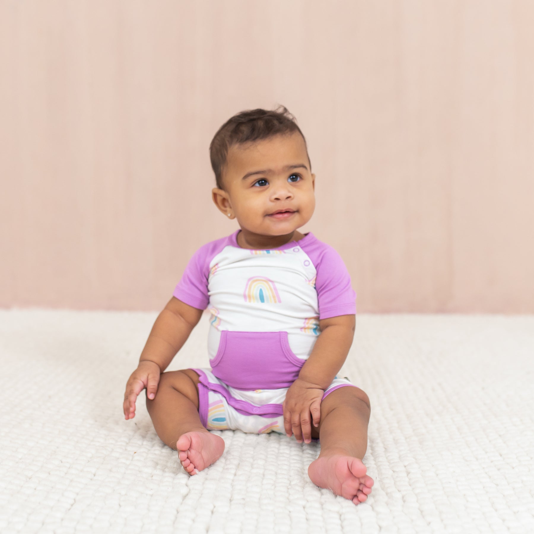 Baby smiling wearing Shortall in Poi Rainbow