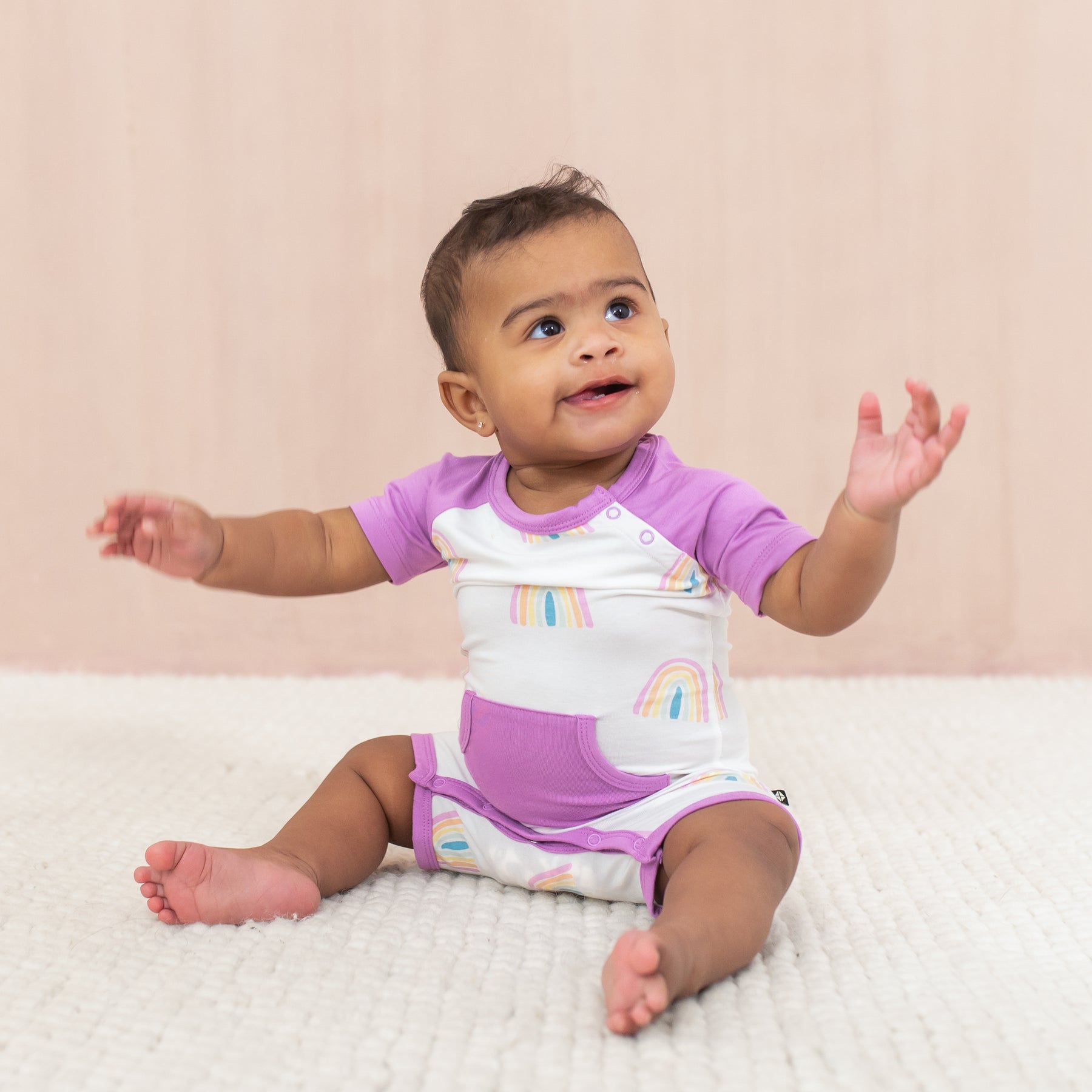 Happy baby wearing Shortall in Poi Rainbow