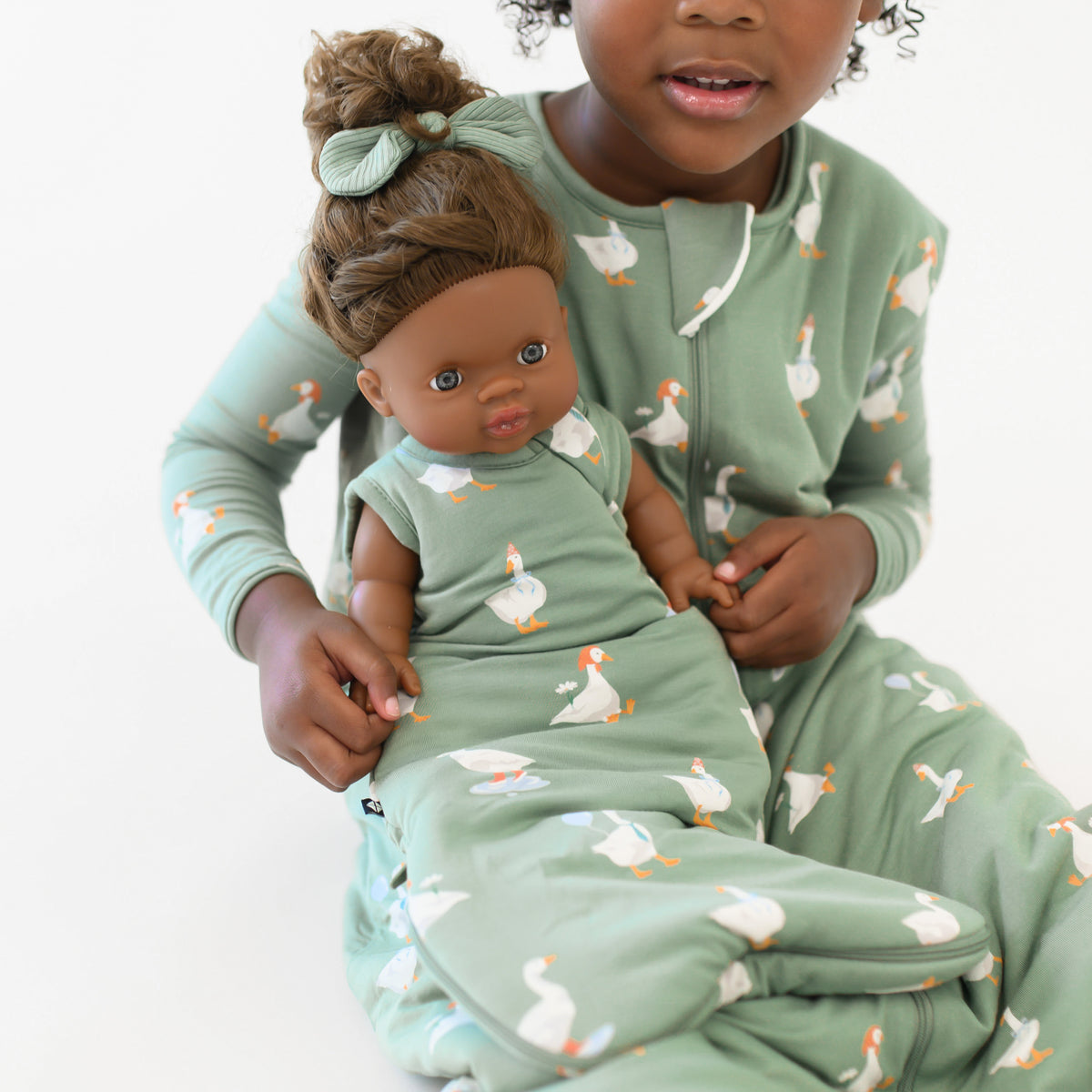Close up of the Baby Doll Sleep Bag in Silly Goose shown on a doll being held by a young girl matching in the Sleep Bag Walker and long sleeve toddler pajamas