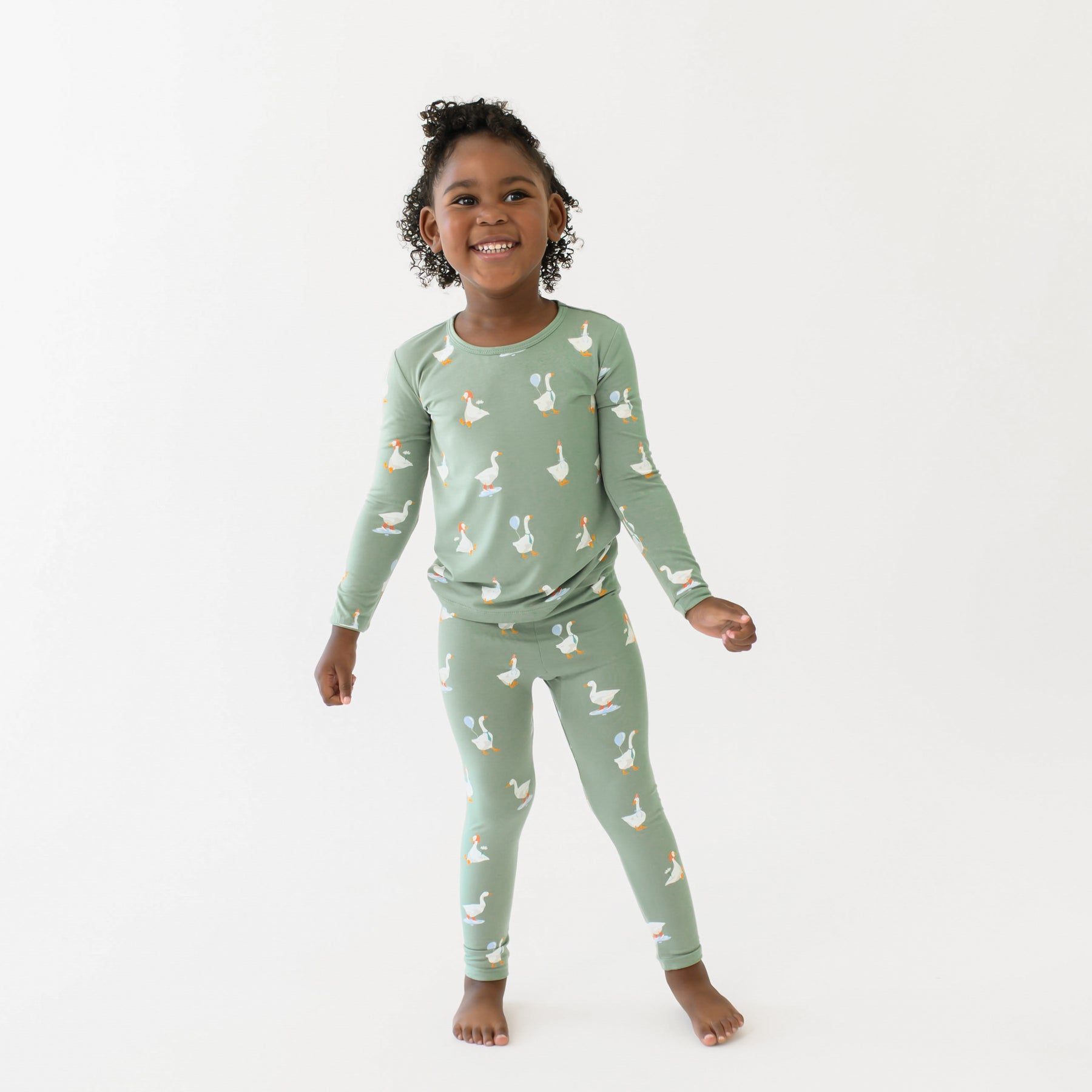 smiling girl standing with her arms out wearing the Long Sleeve Pajamas in Silly Goose in front of a white backdrop