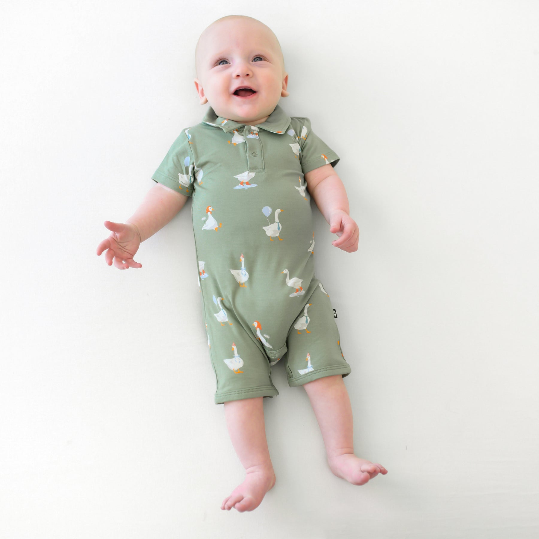 Infant laying down on a light neutral backdrop wearing the Polo Shortall in Silly Goose