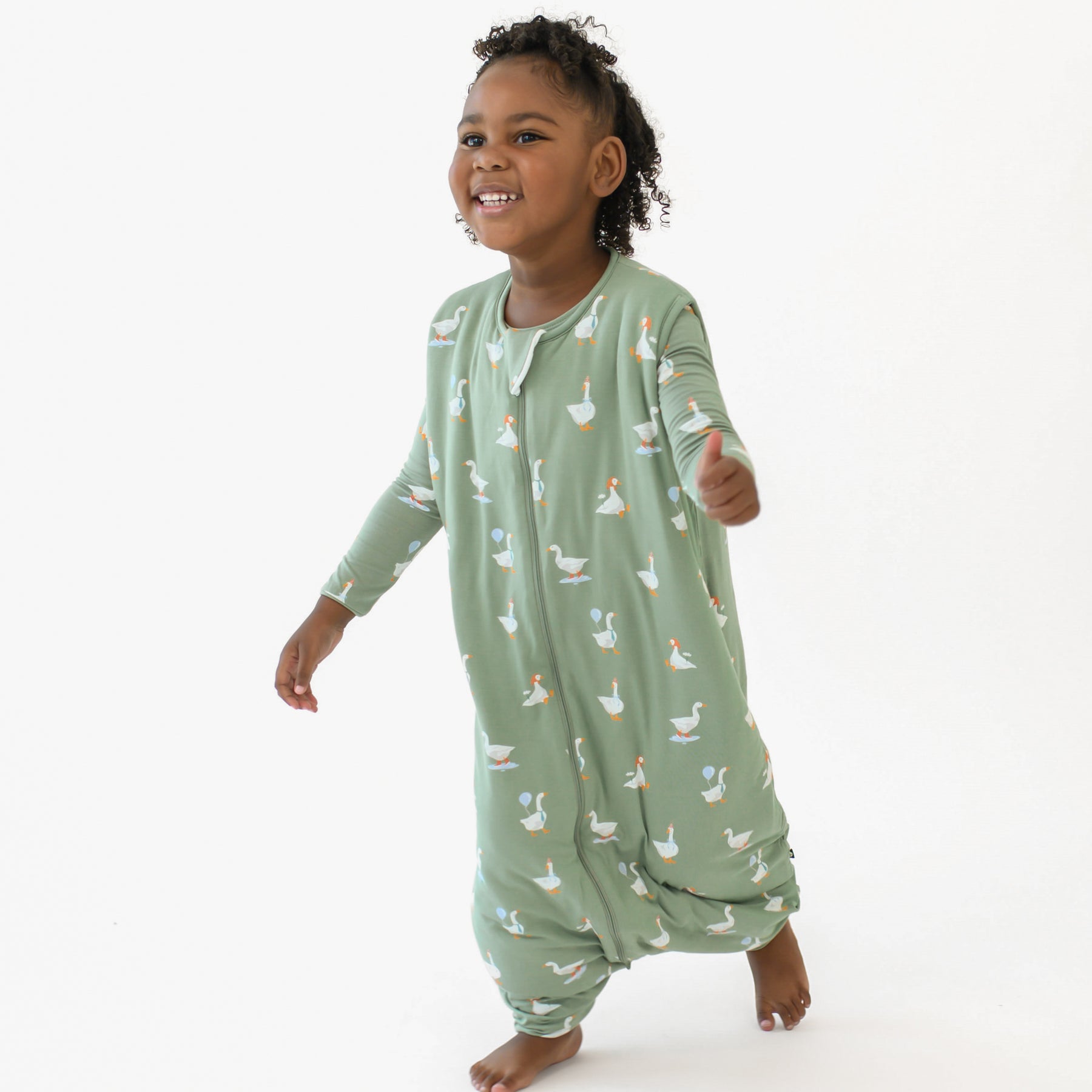 Young girl walking wearing the Sleep Bag Walker in Silly Goose 1.0 with matching long sleeve pajama bottoms on underneath