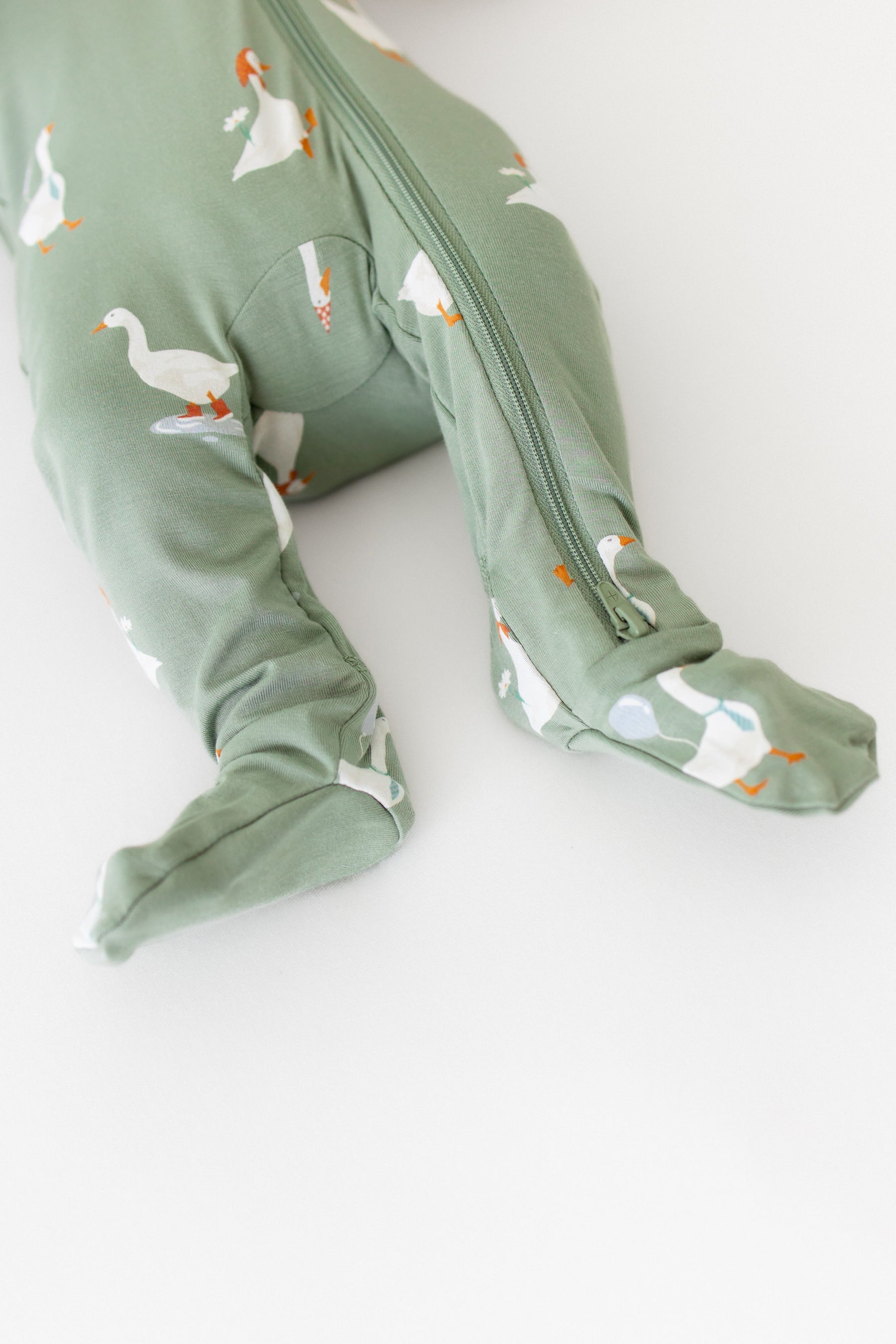 Green baby onesie with goose pattern on a white background