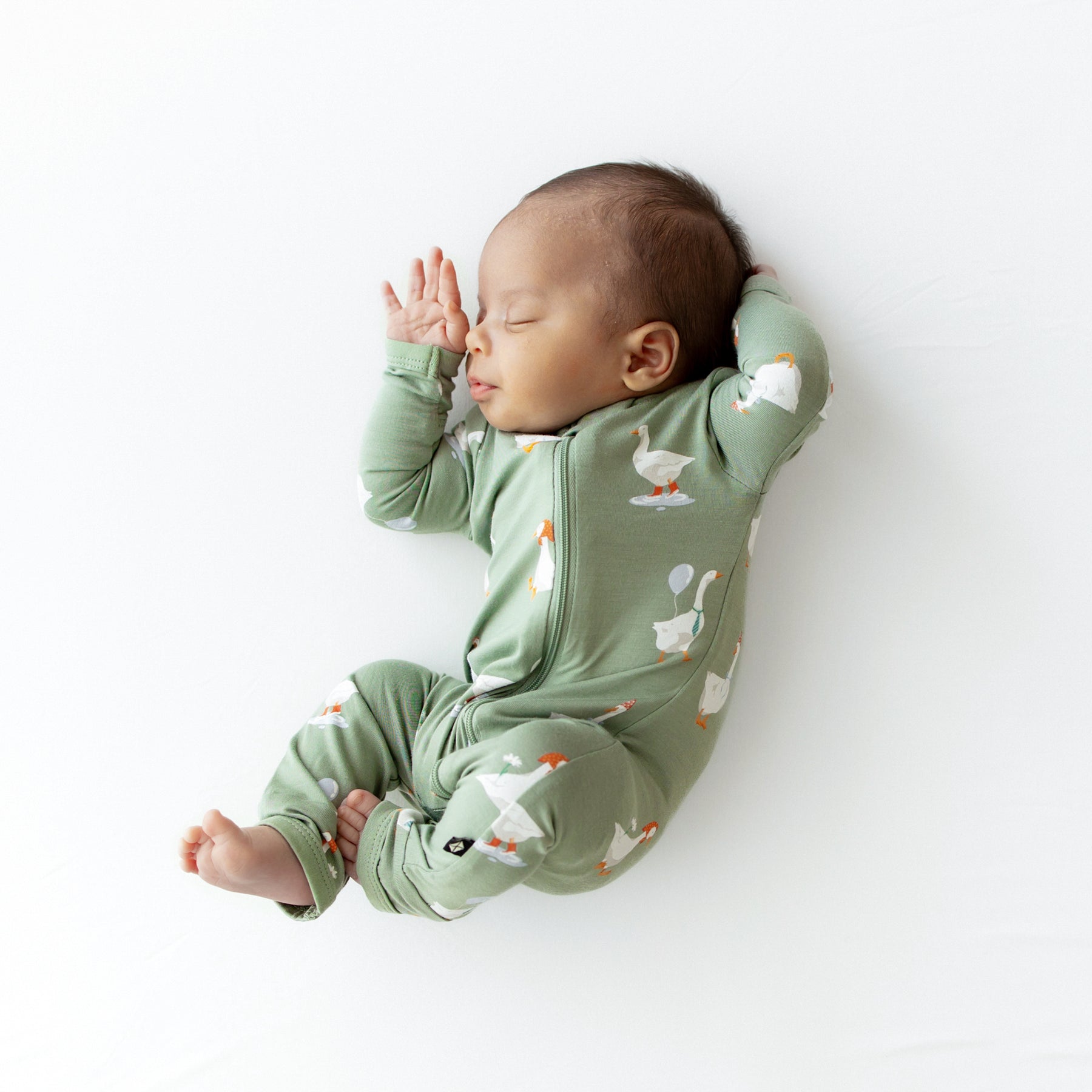 Sleeping newborn scrunched up wearing the Zippered Romper in Silly Goose