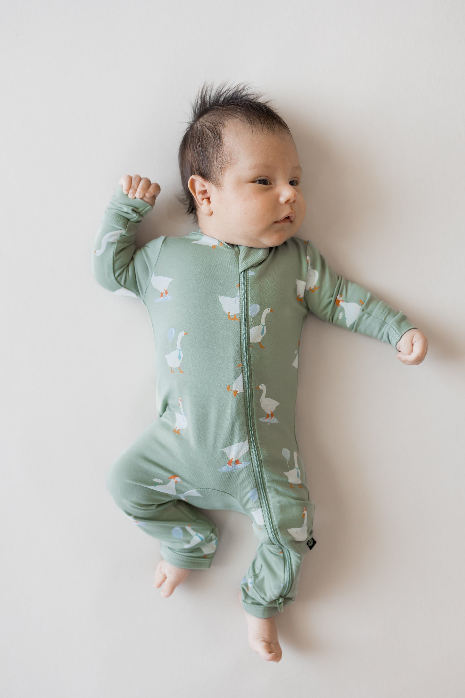 Baby wearing Zippered Romper in Silly Goose print on a beige background