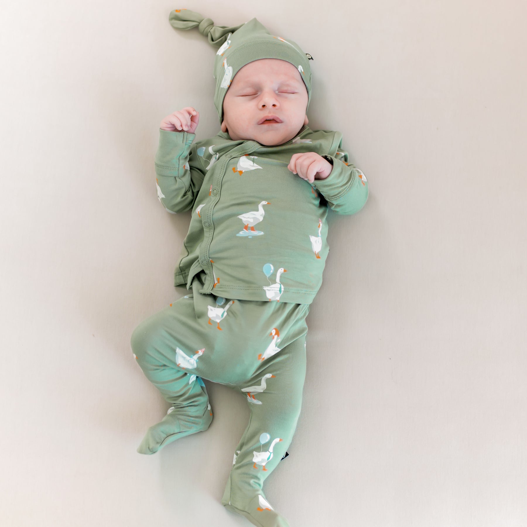 Sleeping newborn wearing the Take Me Home Set in Silly Goose laying on a light neutral background