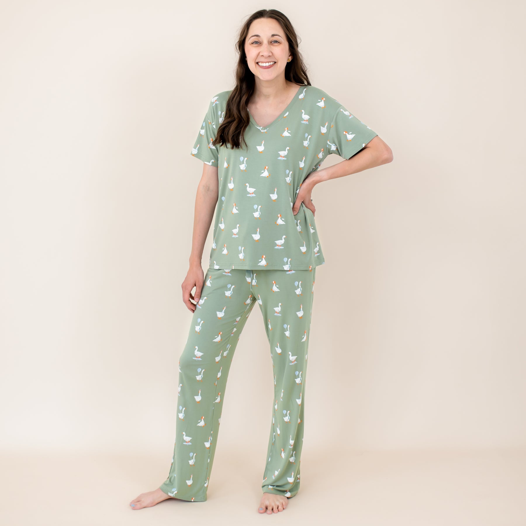 Female model standing with her hand on her hip wearing the Women's Lounge Pants in Silly Goose and matching women's v-neck in front of a light neutral background
