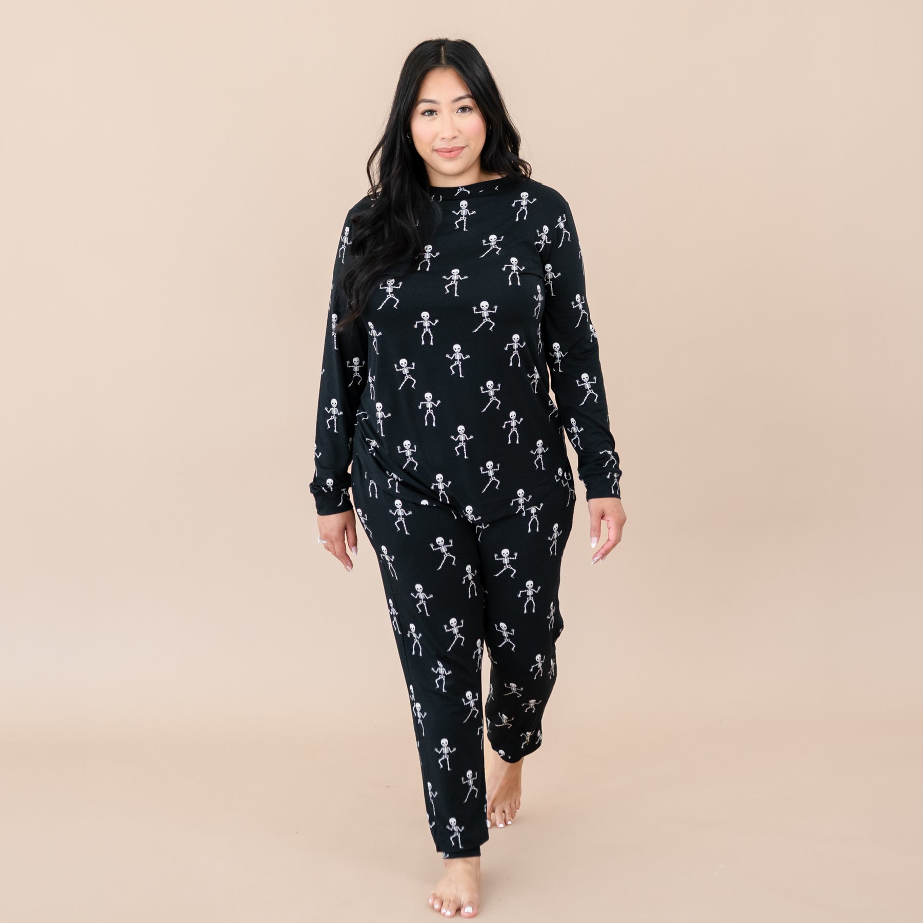 Female model walking wearing the Women's Jogger Pajama Set in Skeleton in front of a light beige backdrop
