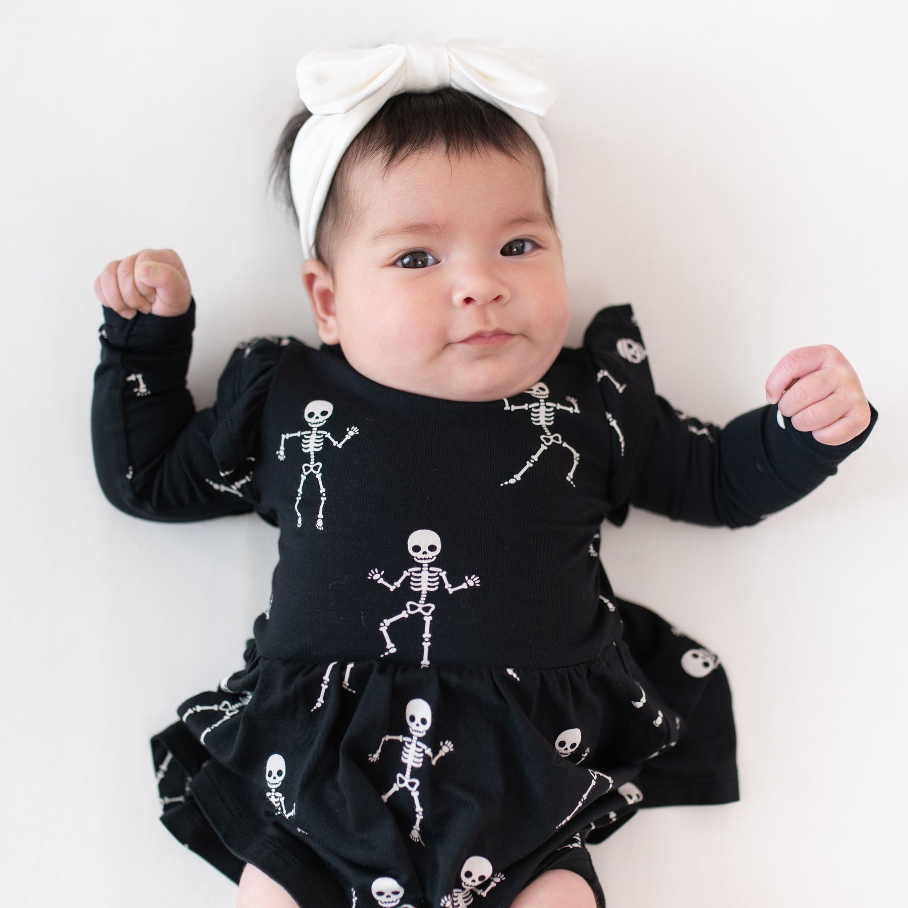 Baby wearing a black dress with skeleton patterns on a white background