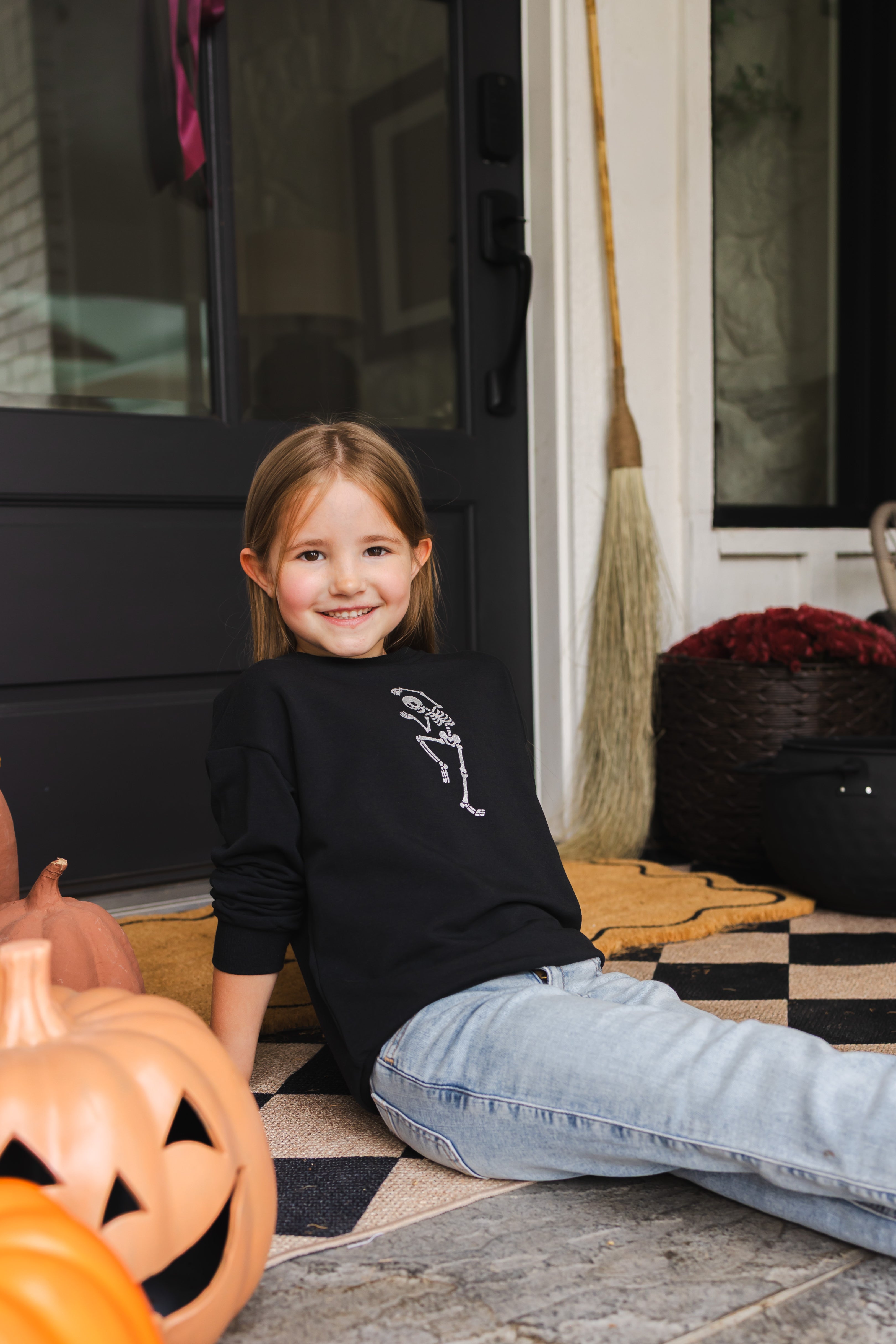Girl sitting outdoors wearing Black Sweatshirt with Skeleton print in the center