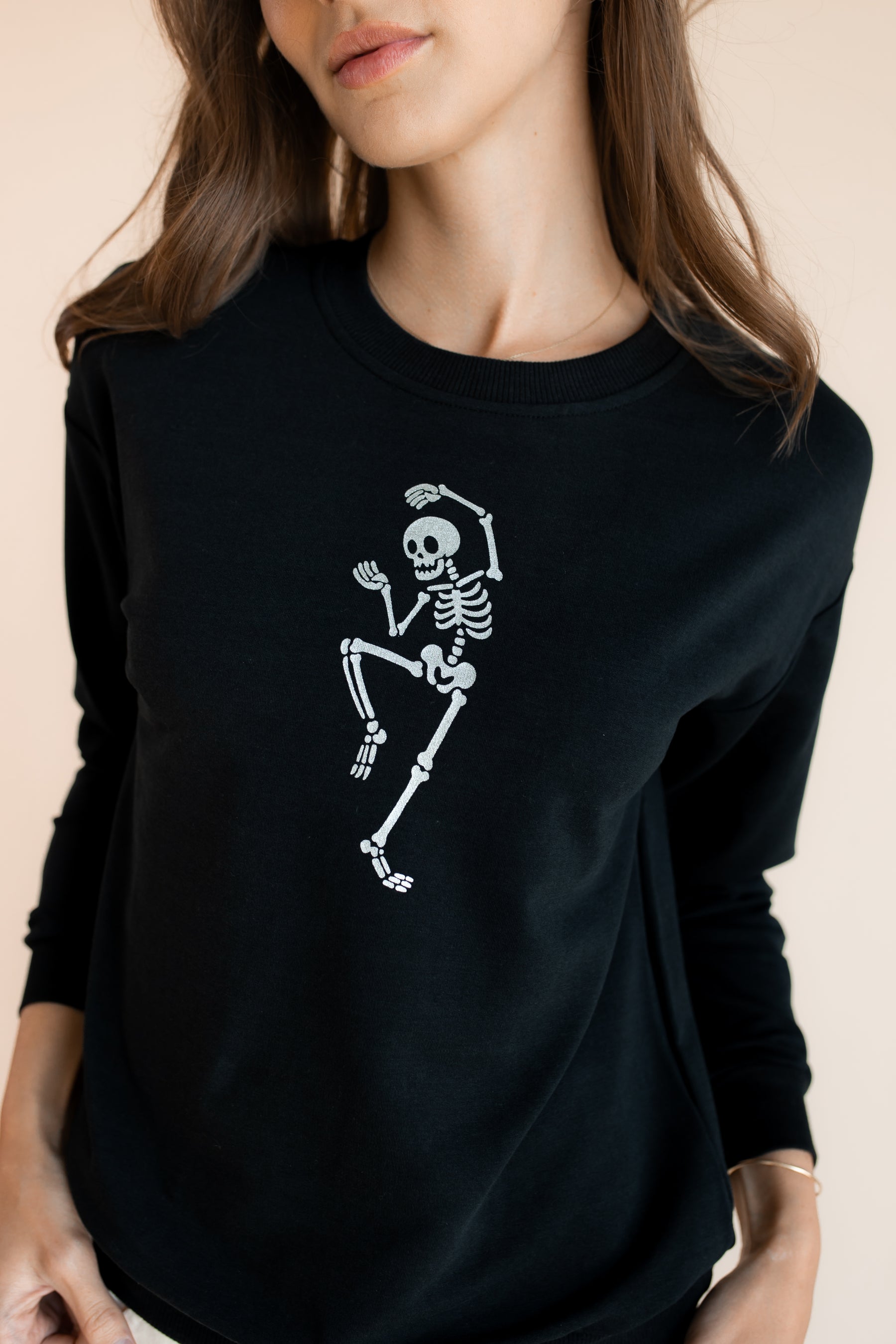Close up of Modal wearing Black Women's Sweatshirt with Skeleton print in the center on a beige background