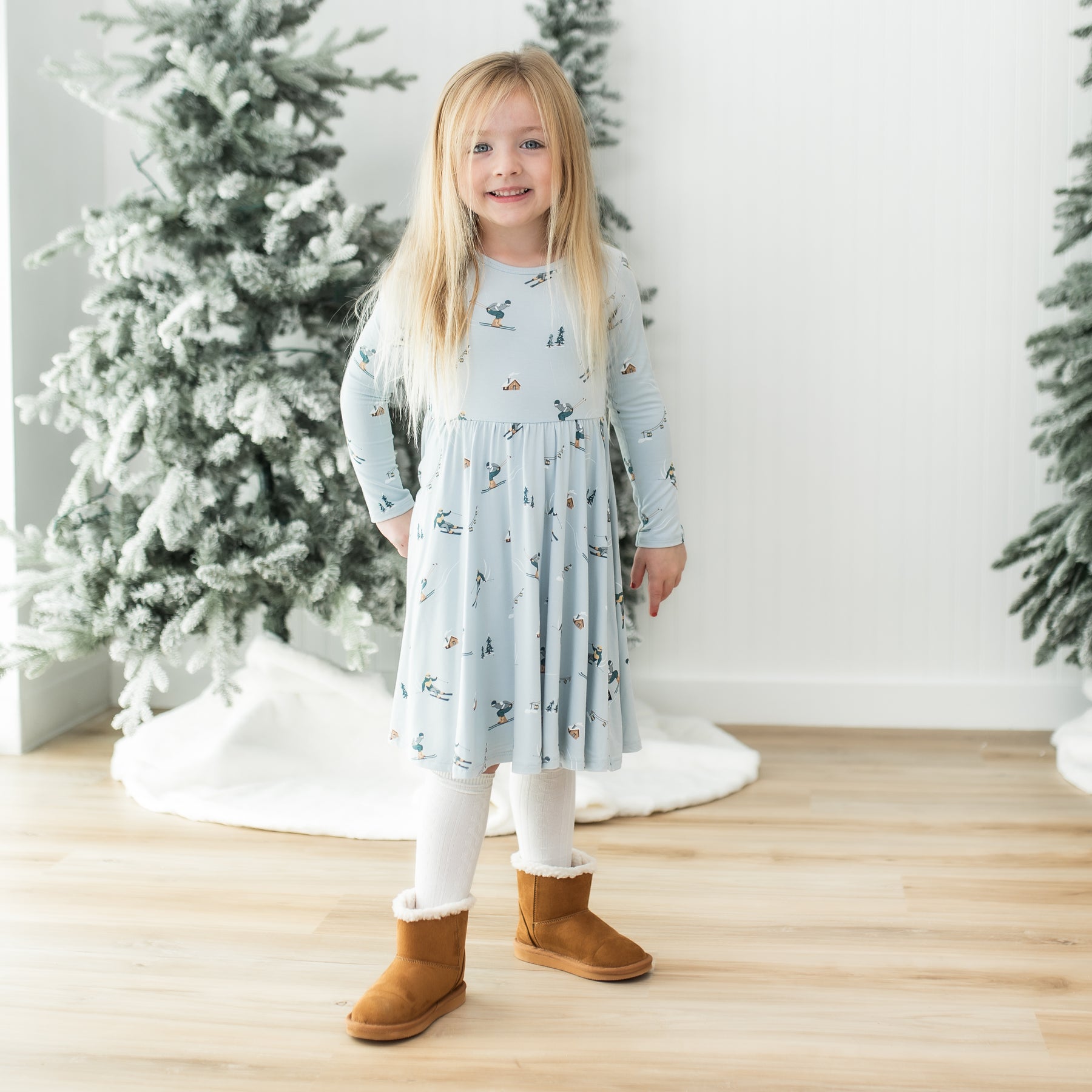Young girl standing in front of frosted trees wearing the Long Sleeve Twirl Dress in Ski