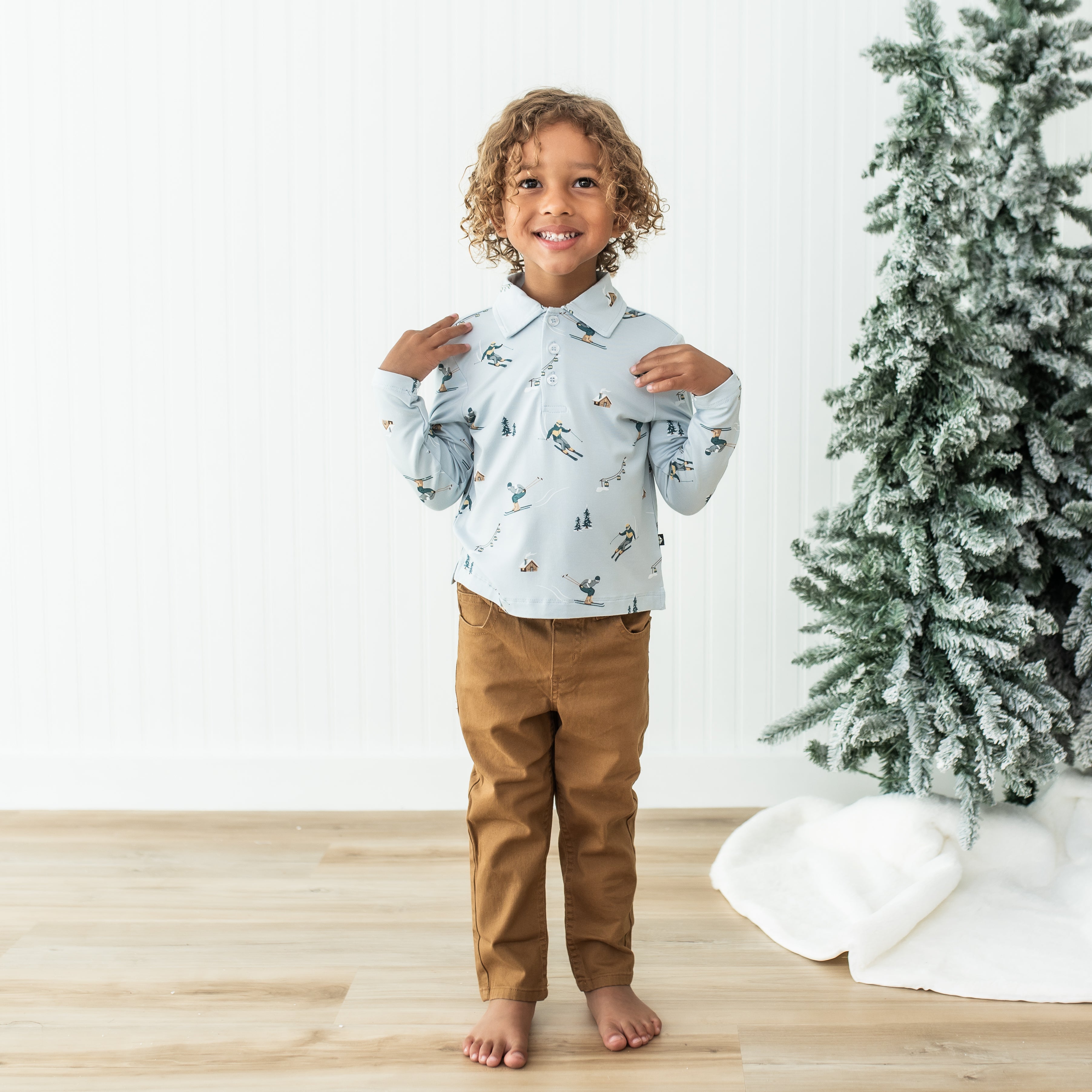 Young boy standing wearing the Toddler Long Sleeve Polo in Ski with bronze colored pants